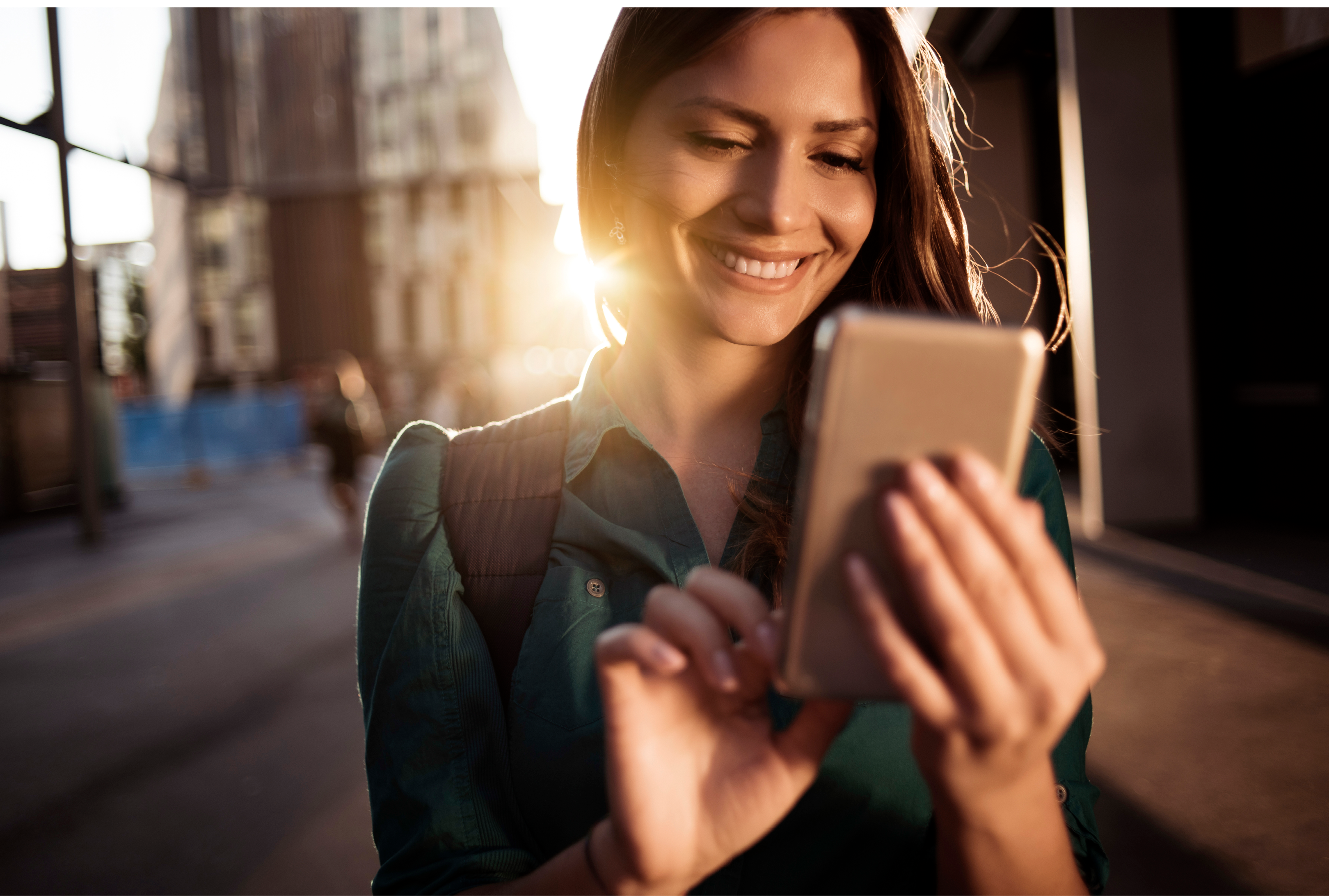 Young happy woman using smartphone in the street