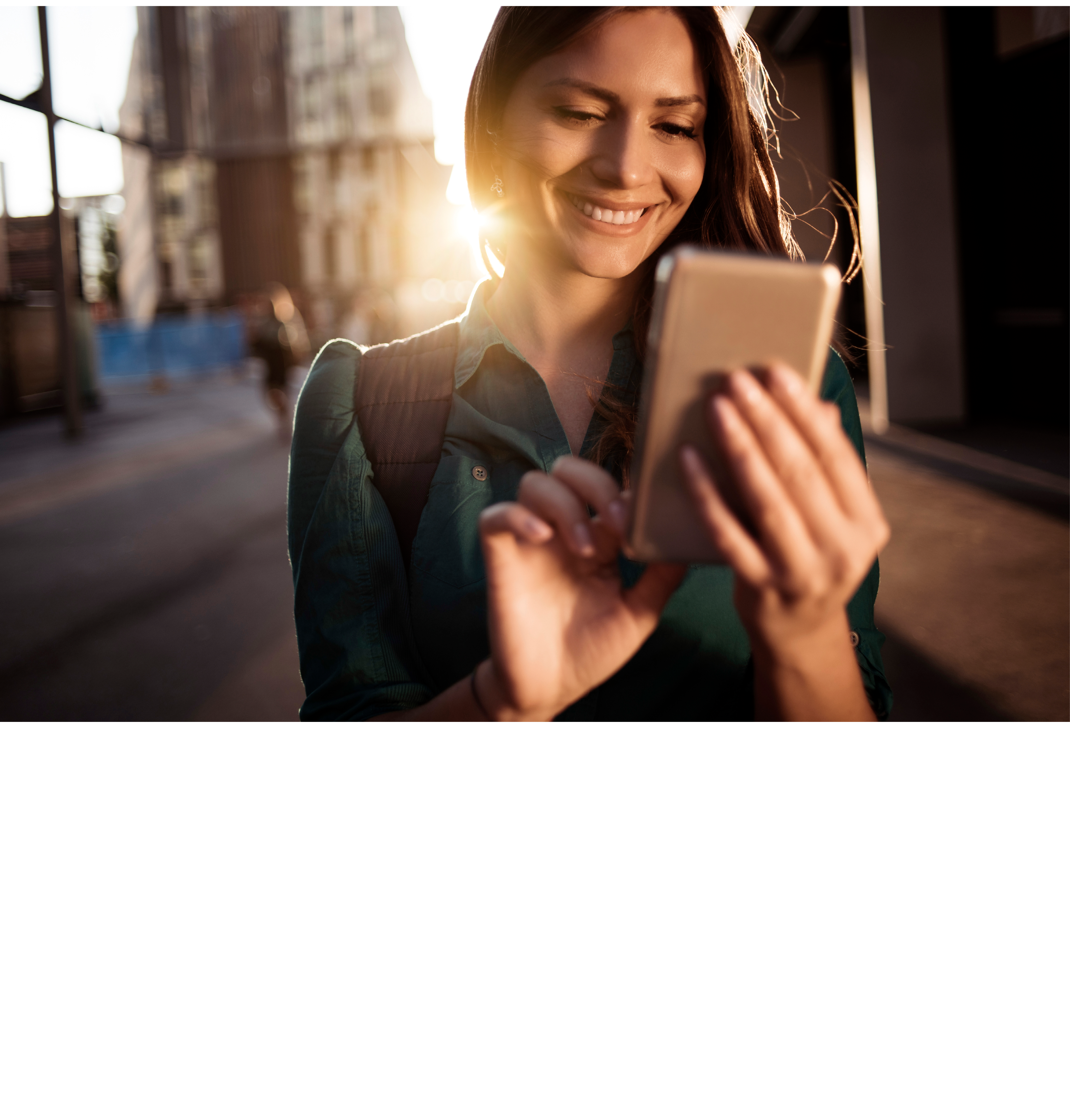 Young happy woman using smartphone in the street