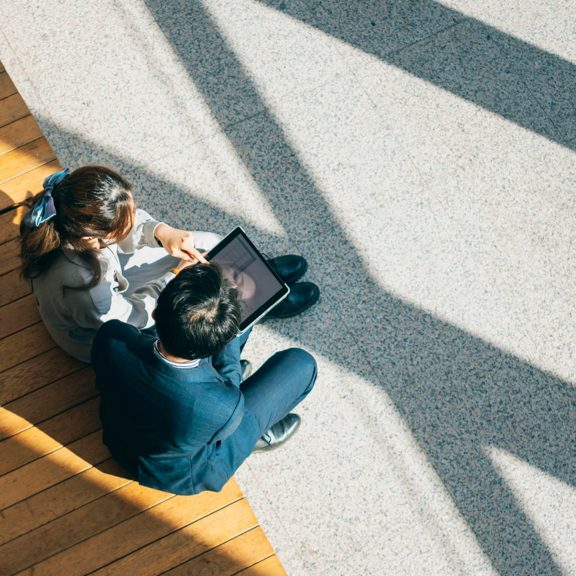 Two businesspersons are seated on chairs in the lobby, seen from a high angle view, engaged in a focused discussion regarding business matters. The lobby might be a spacious and comfortable area, and they could be discussing business strategies, plans, or other work-related topics. Their expressions might convey professionalism and concentration, depicting a scenario of communication and discussion within a business environment.