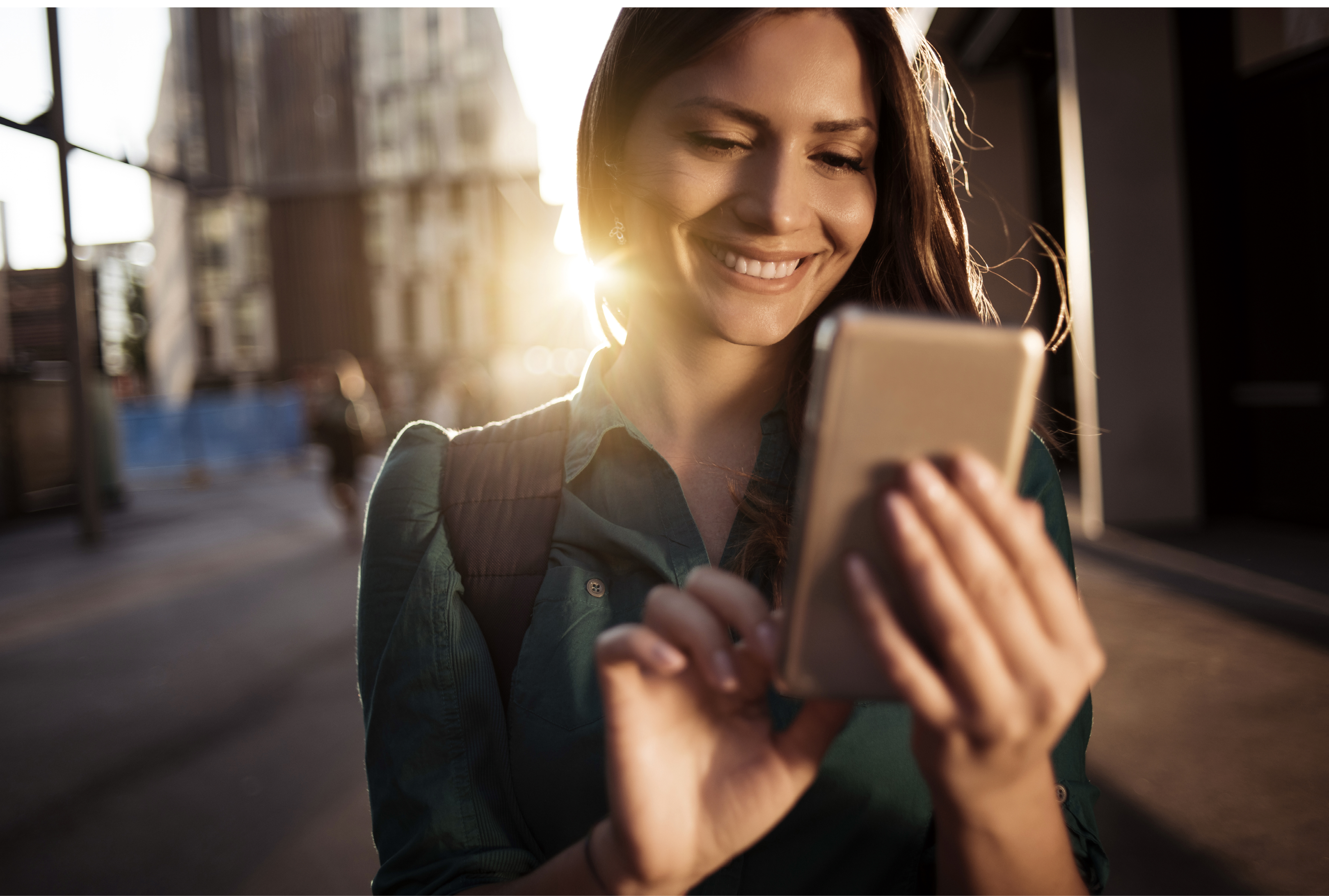 Young happy woman using smartphone in the street