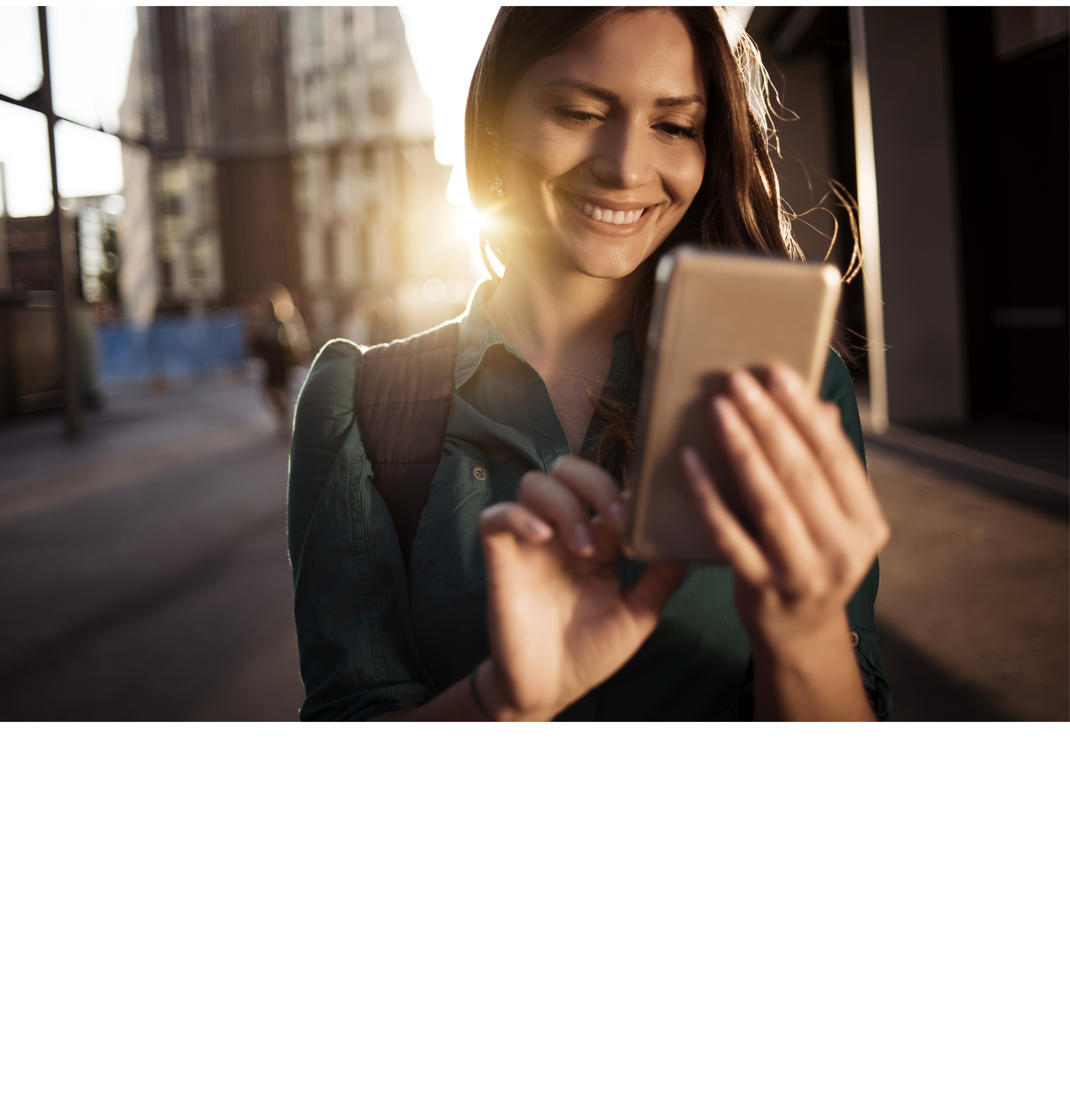 Young happy woman using smartphone in the street