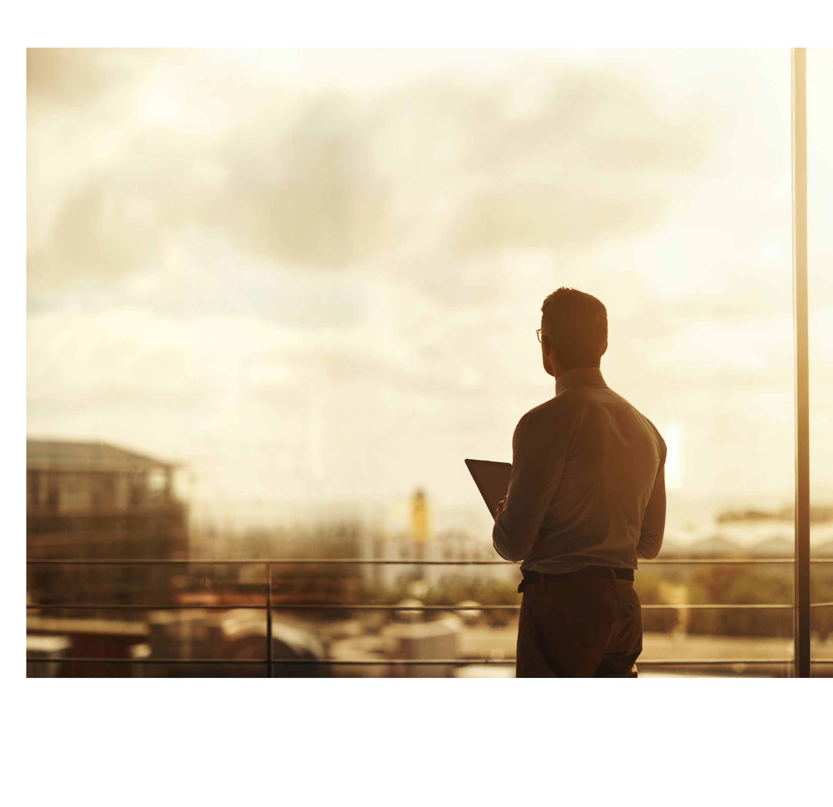 Silhouette of a mature businessman standing in front of an office window and using a digital tablet