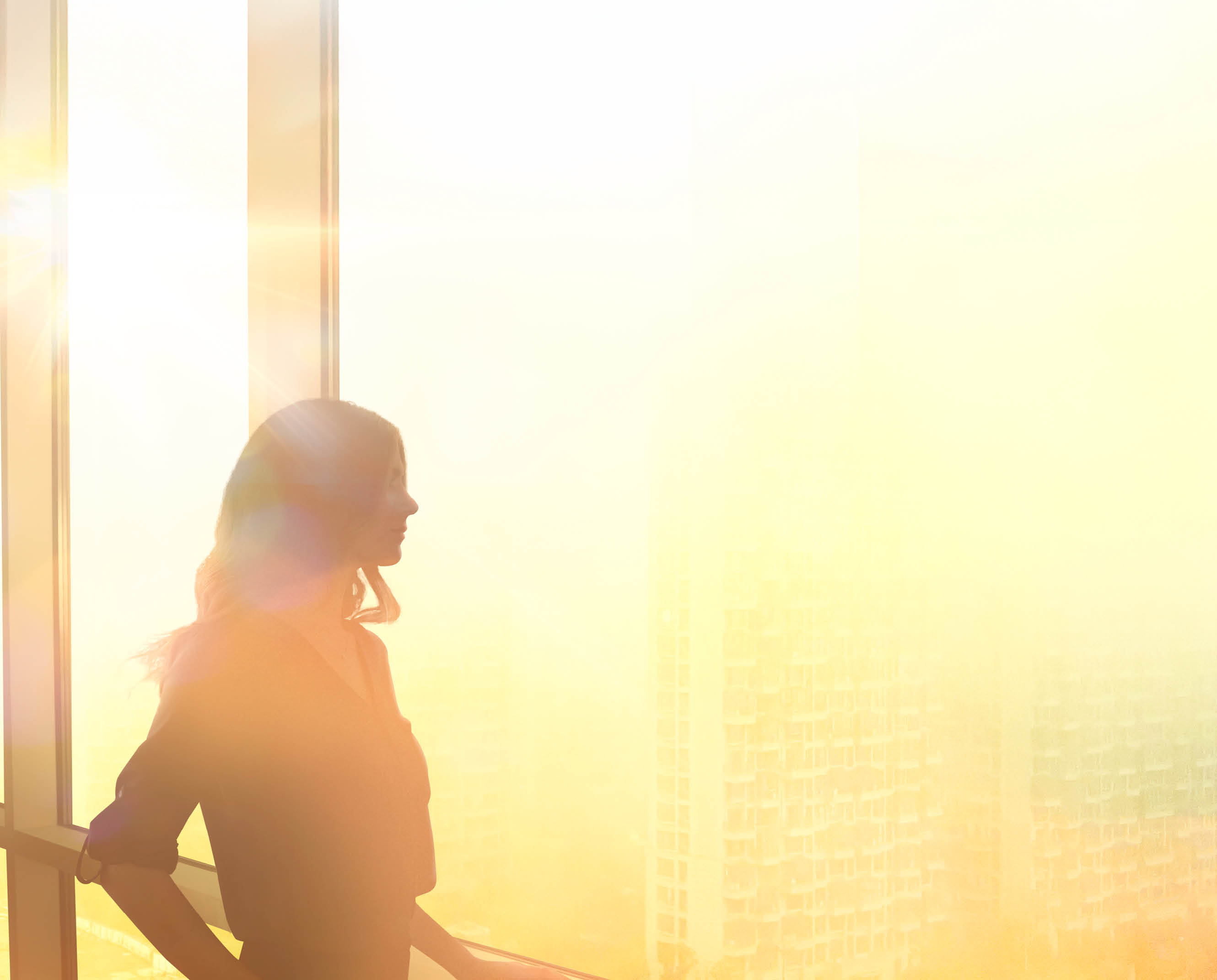 CEO woman looking out skyscraper window dreaming big