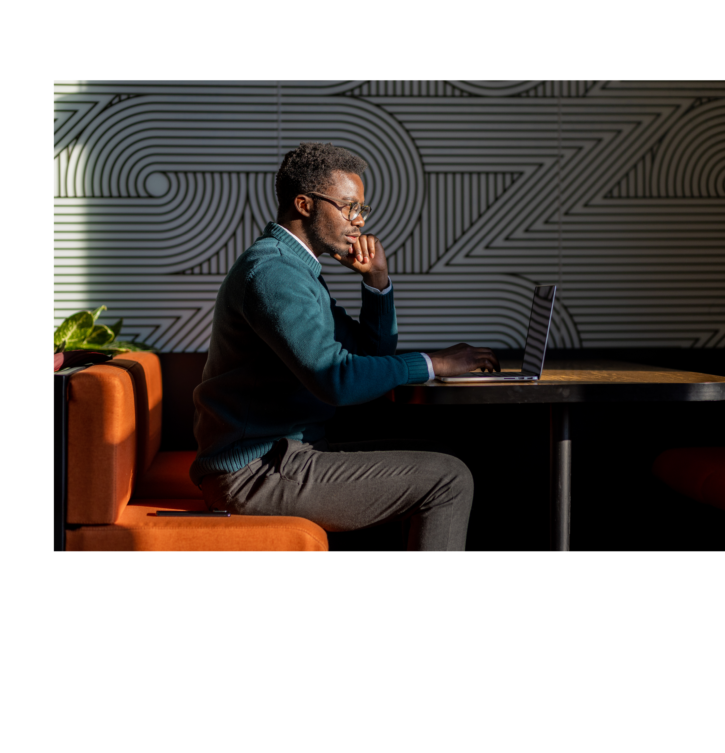 Young black businessman in a coworking space, new office, modern environment. Young African-American freelancer working on his laptop in a beautifully sunlit space.
