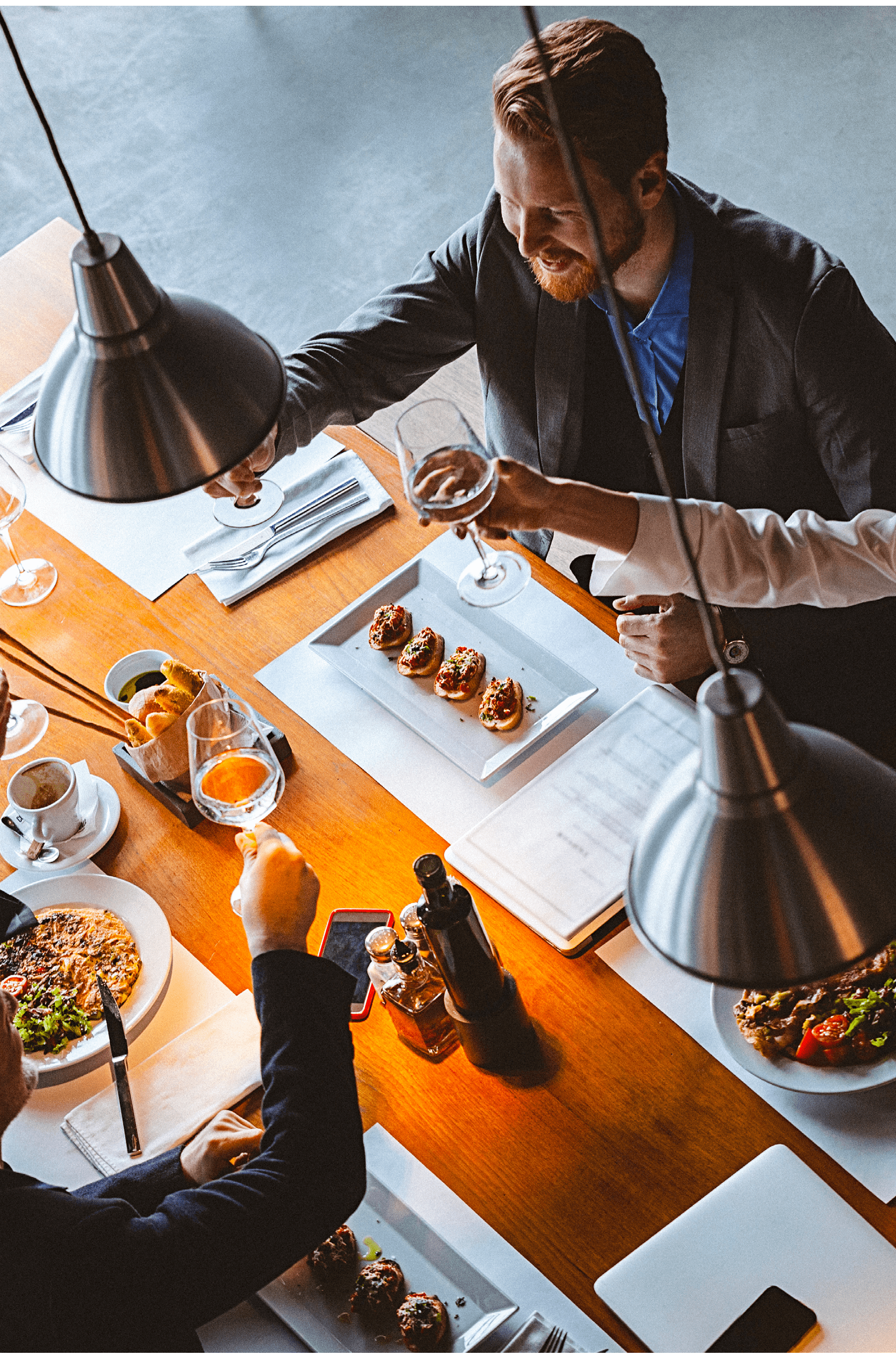 High angle view photo of a group of friends toasting during lunch time in a high-end reastaurant  It could be that they are business people having a business lunch  All are well dressed  The shot is executed with available natural light and the copy space has been left 