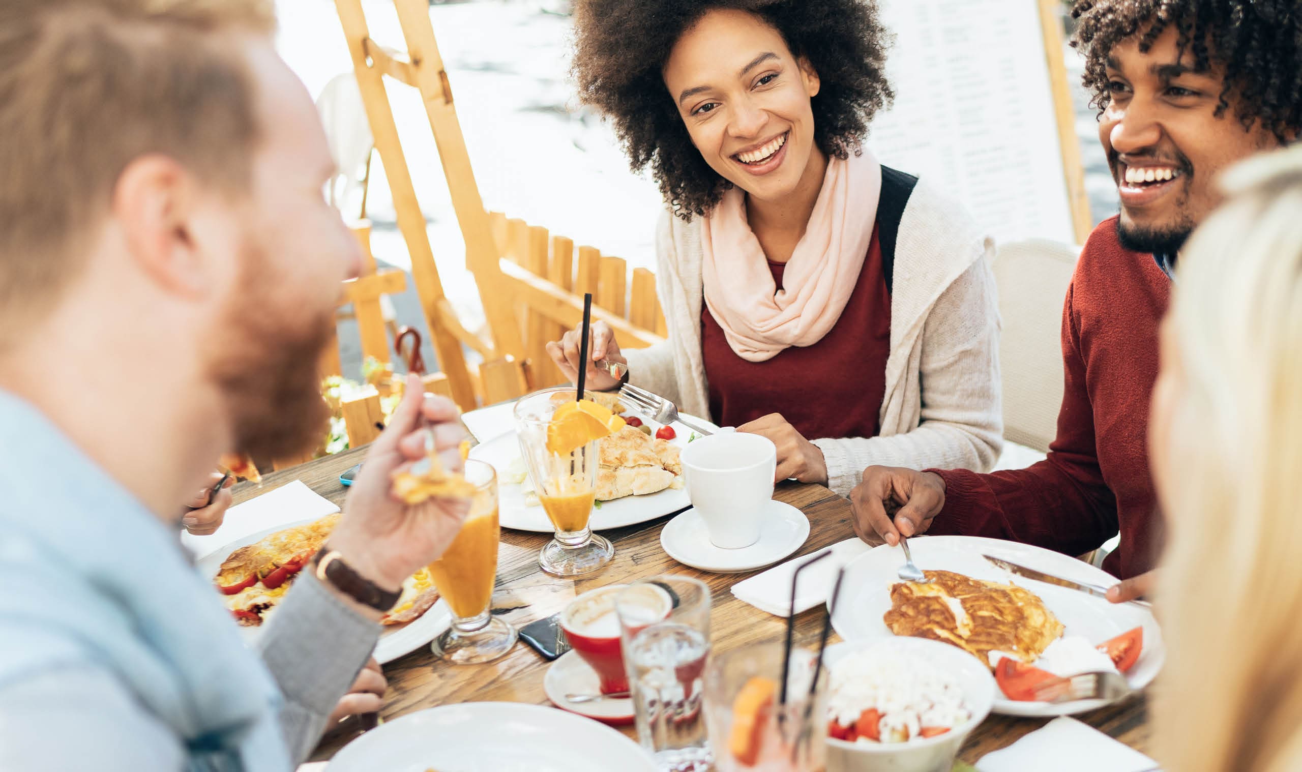Multi-ethnic group of friends at restaurant outdoor having great time together