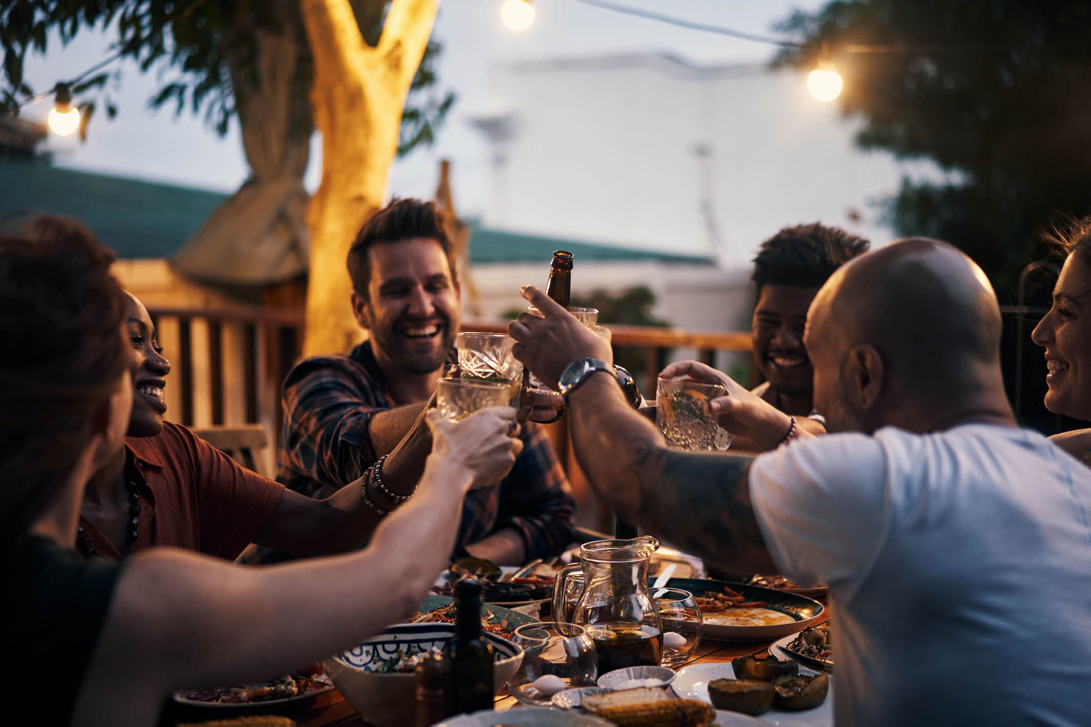 Shot of a group of young friends toasting with drinks at a dinner party outdoors