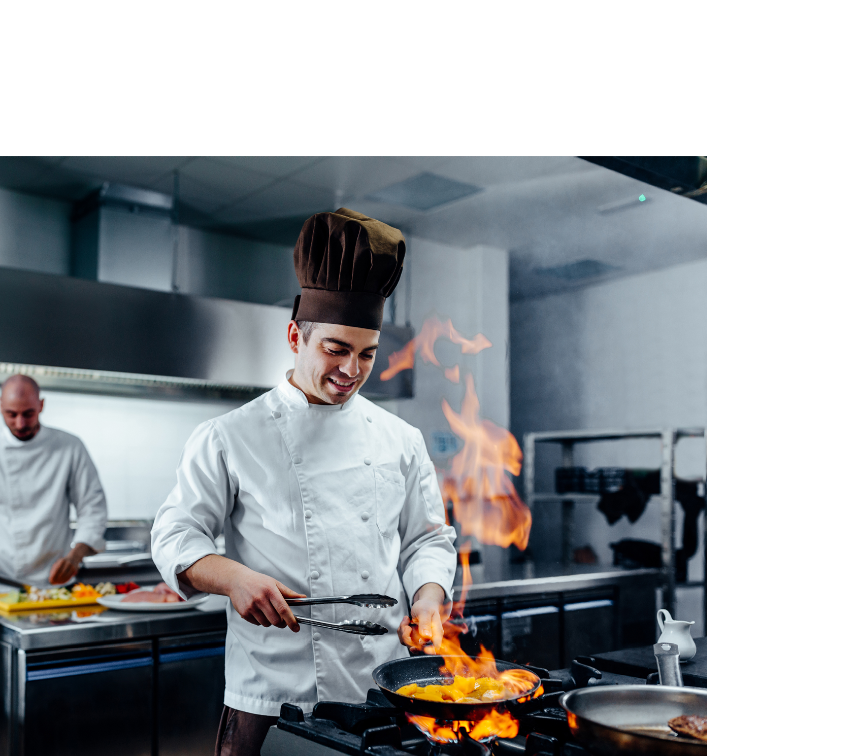 Cropped shot of a young male chef flambeing in a professional kitchen