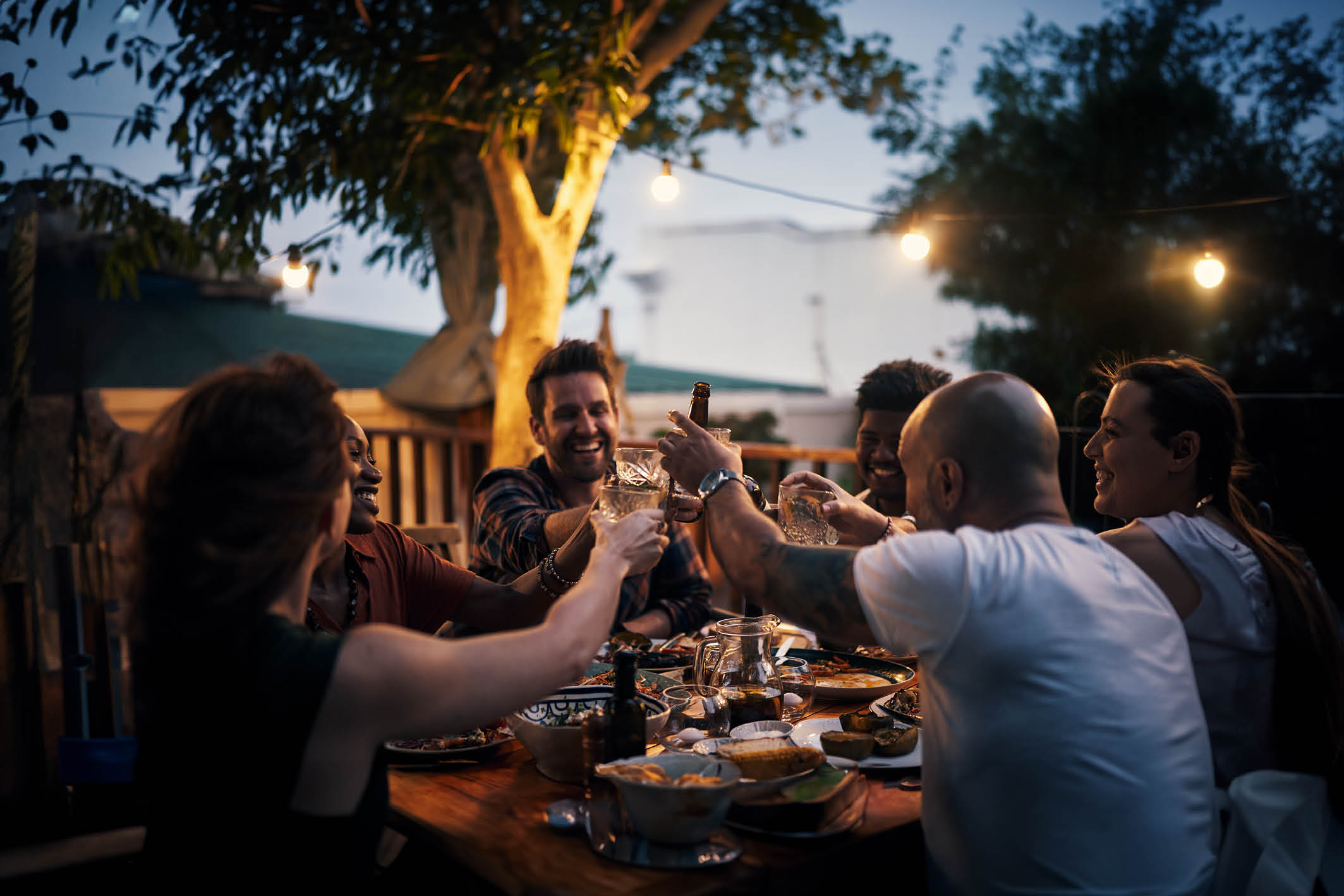 Shot of a group of young friends toasting with drinks at a dinner party outdoors