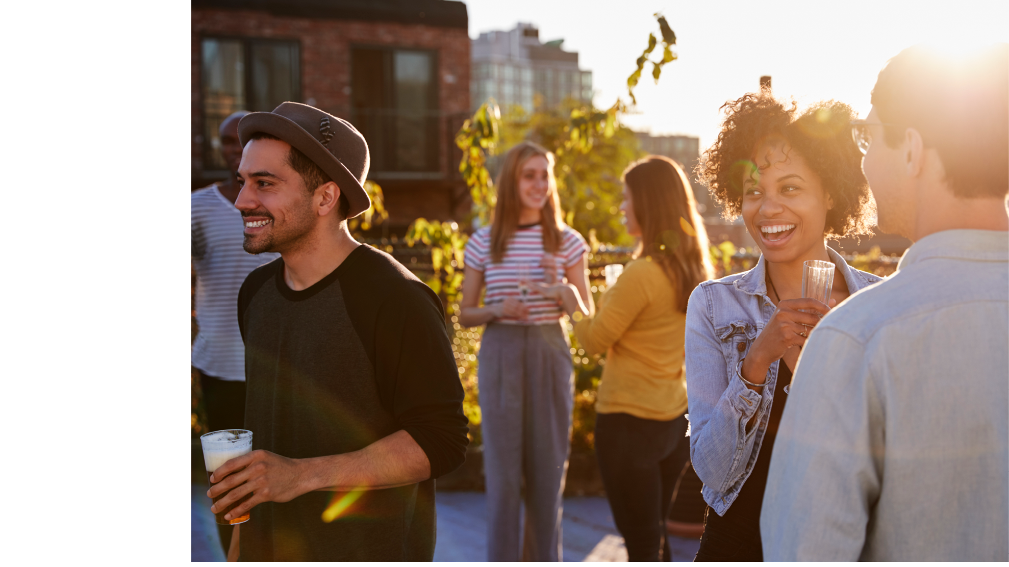 Happy friends at a rooftop party backlit by sunlight