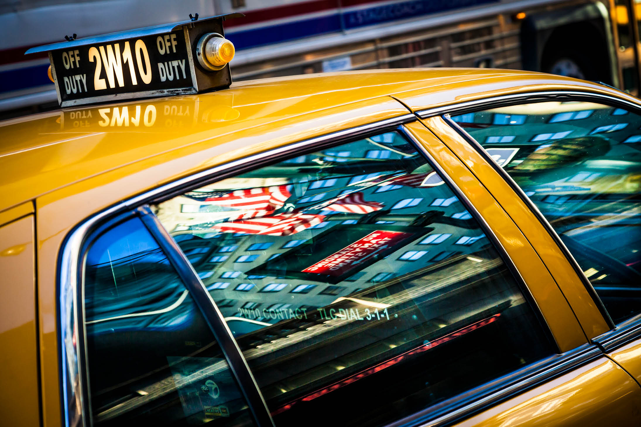 Reflection of Times Square and the Star and stripes in the window of a yellow cab in New York City.