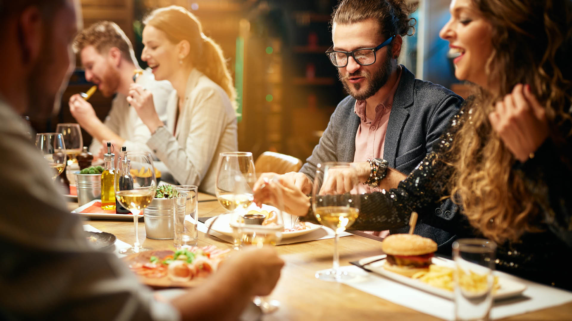 Group of cheerful best friends sitting in restaurant, chatting and eating diner.