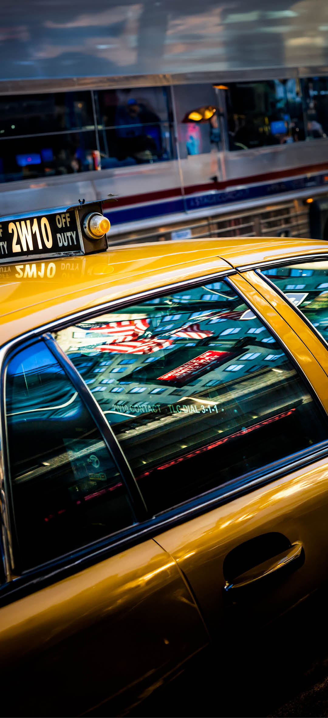 Reflection of Times Square and the Star and stripes in the window of a yellow cab in New York City.