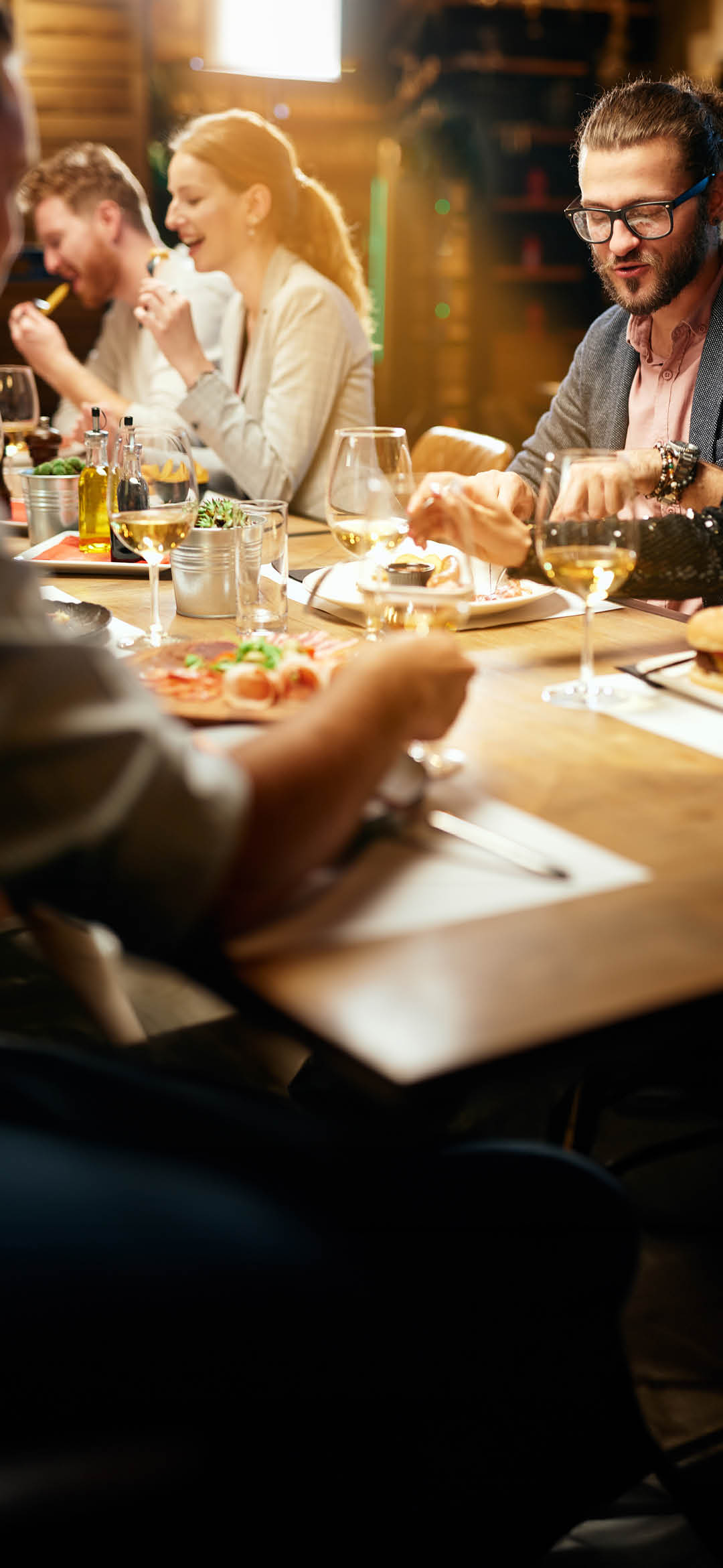 Group of cheerful best friends sitting in restaurant, chatting and eating diner.