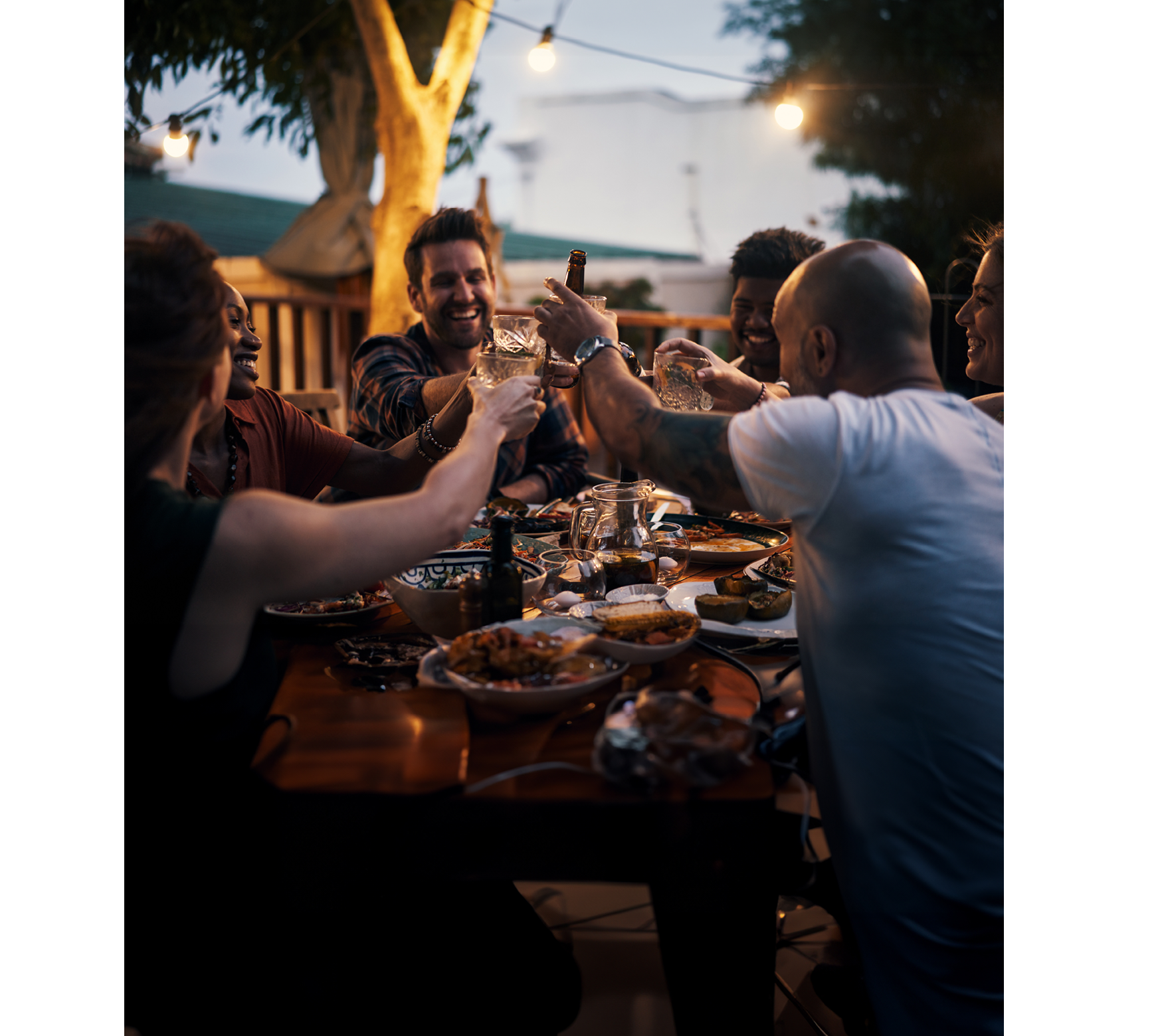 Shot of a group of young friends toasting with drinks at a dinner party outdoors