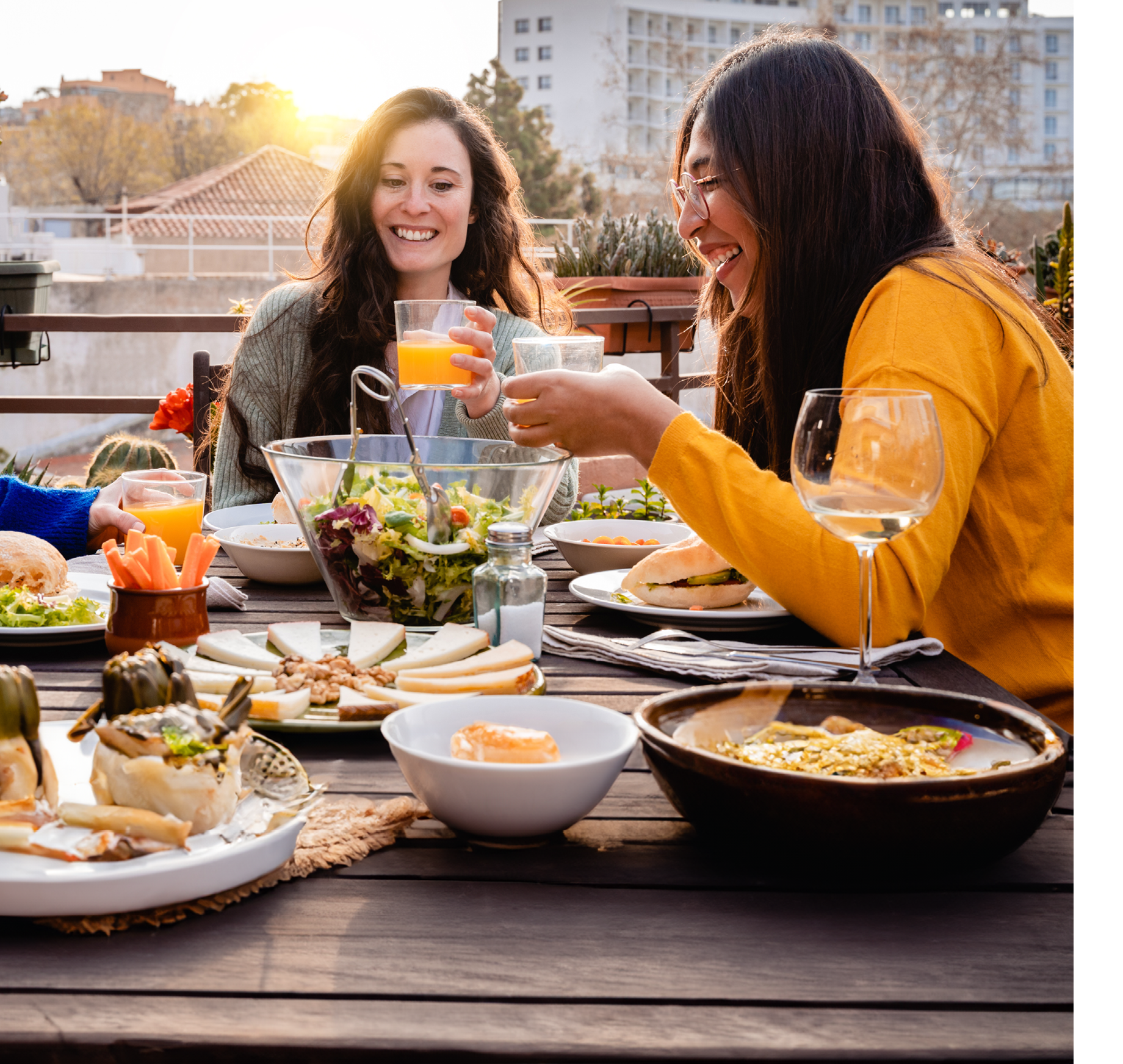 Happy friends having fun eating vegan food outdoor with sunset background - Focus on center girl hand holding glass of juice