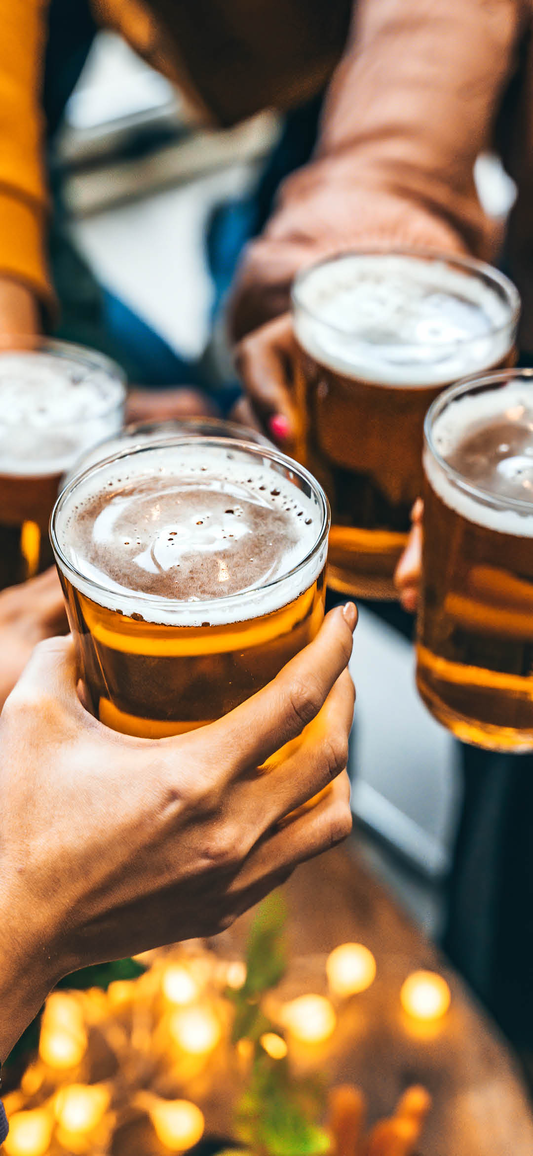 Group of friends drinking and toasting glass of beer at brewery pub restaurant- Happy multiracial people enjoying happy hour with pint sitting at bar table- Youth Food and beverage lifestyle concept