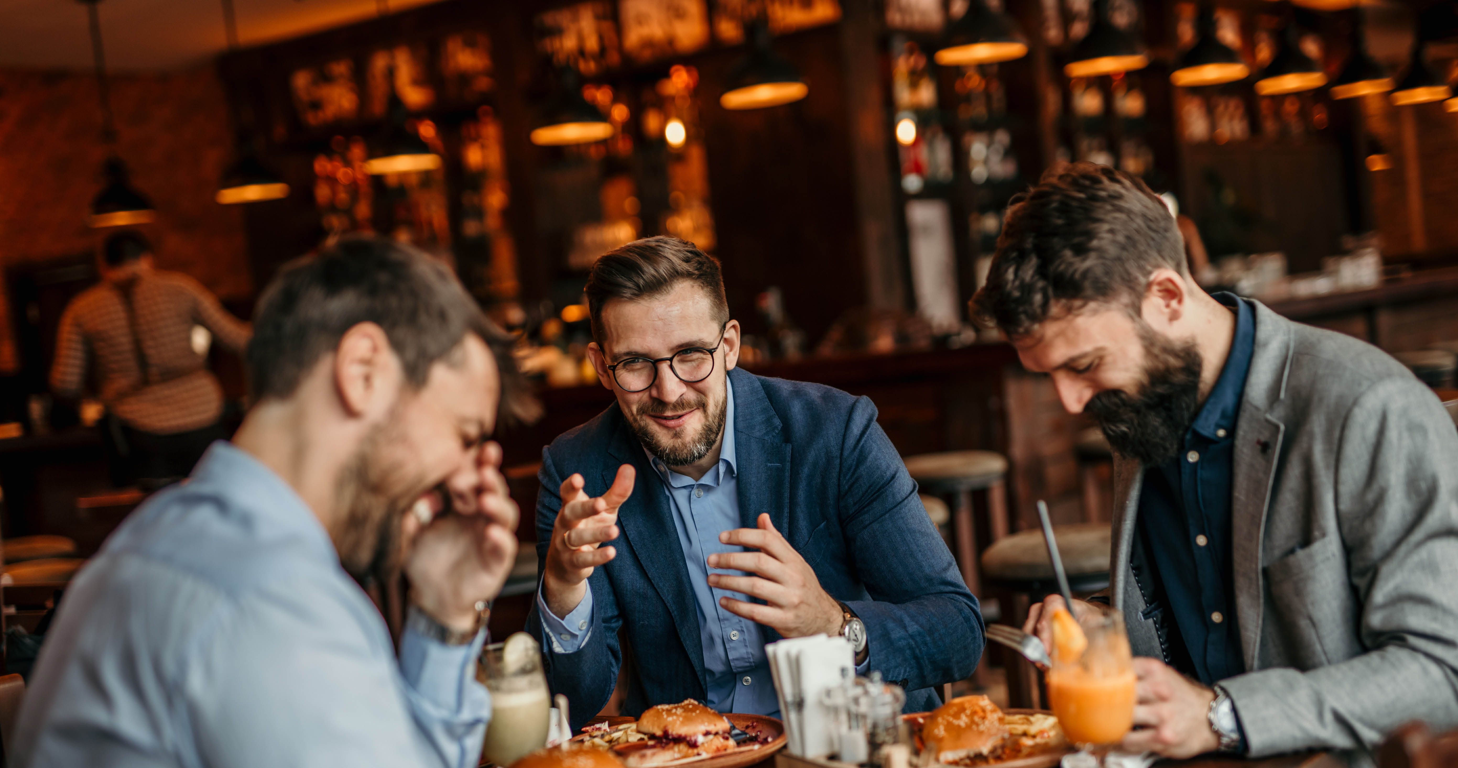 Group of businessmen enjoying a burger lunch while discussing work matters