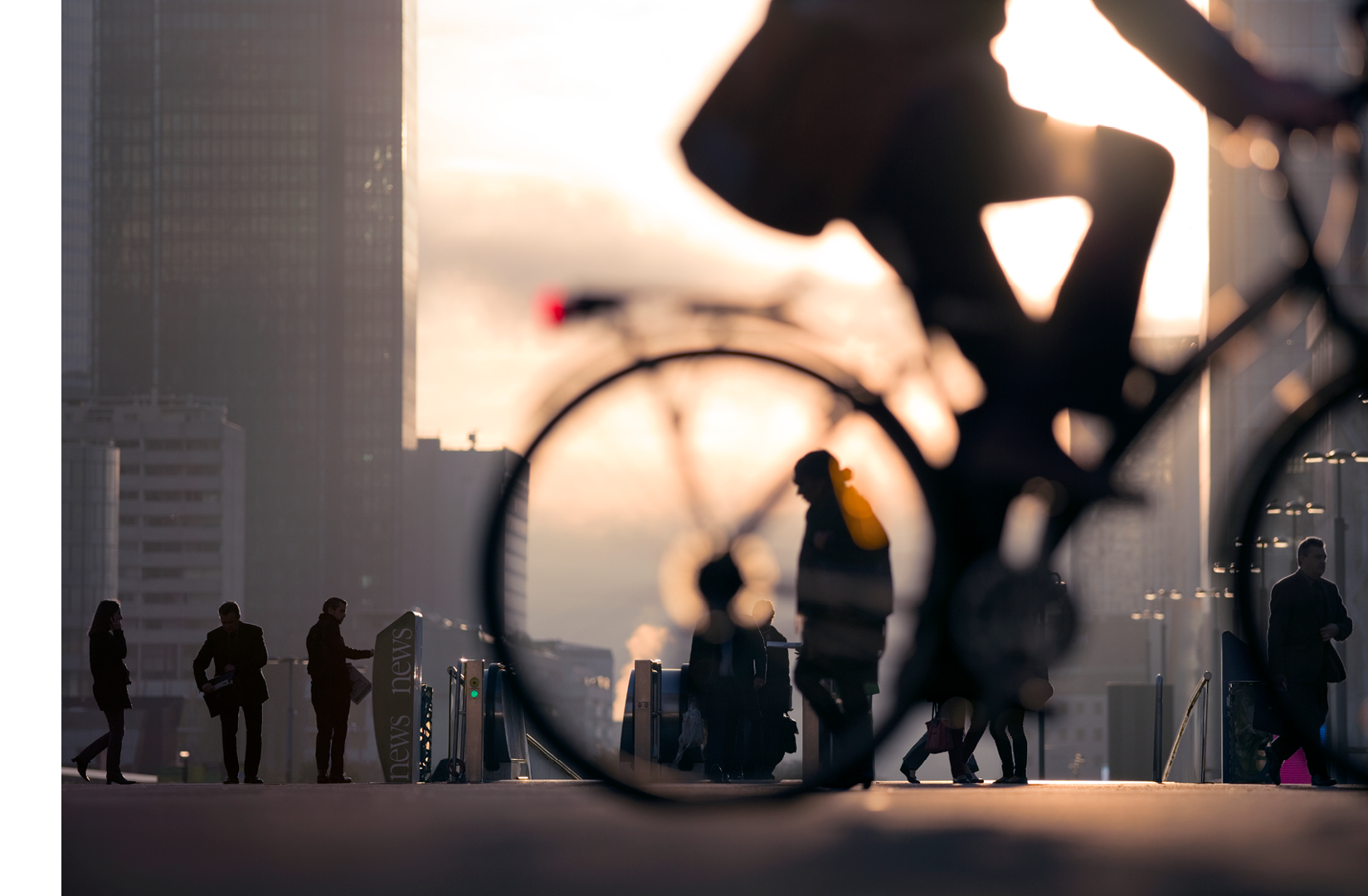 Morning image of businessman on bicycle passing skyline of La Defense business district in Paris, France.