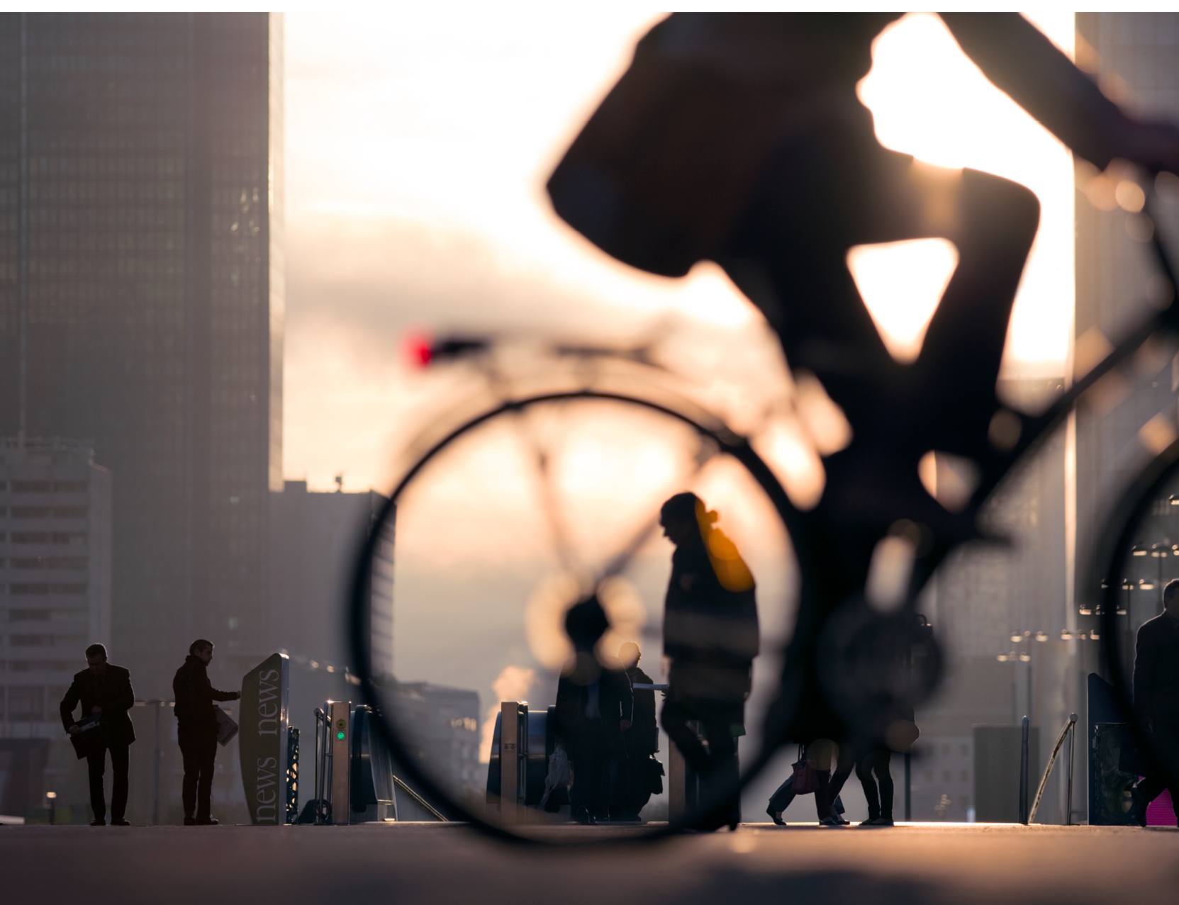 Morning image of businessman on bicycle passing skyline of La Defense business district in Paris, France.