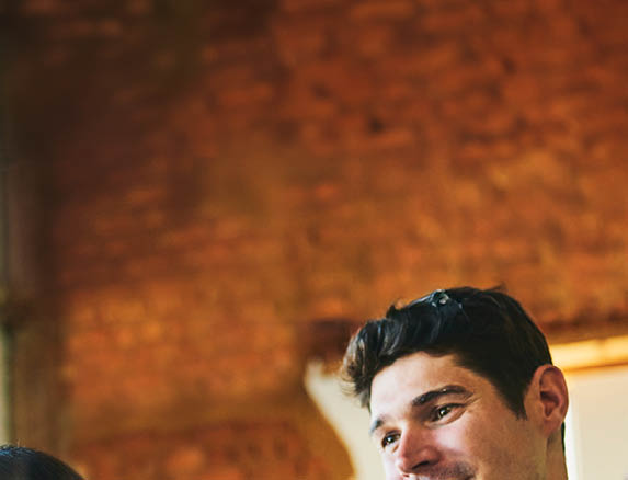 Businesswoman and male colleagues smiling and looking interestingly at sticky notes on glass wall in office