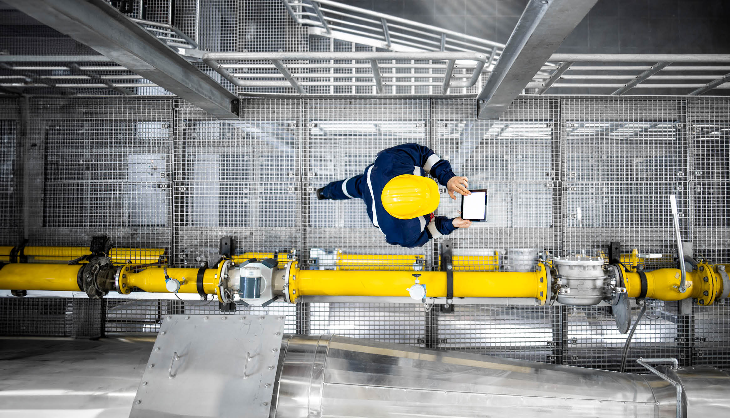 Top view of refinery worker walking by gas pipes, checking gasoline supply and installations in production plant.