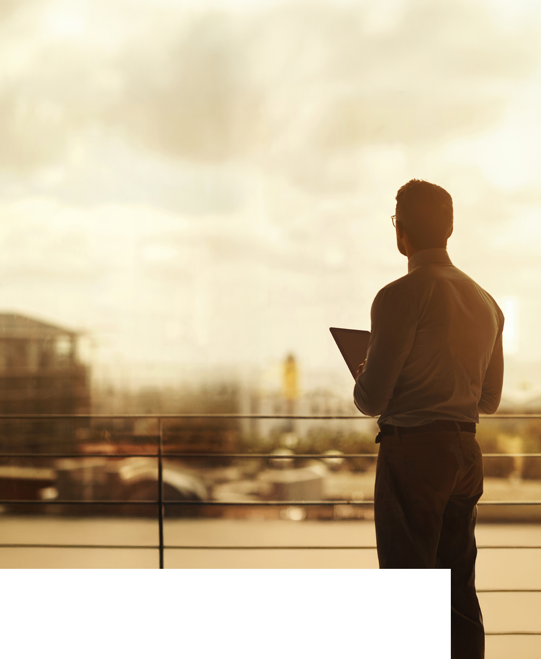 Silhouette of a mature businessman standing in front of an office window and using a digital tablet
