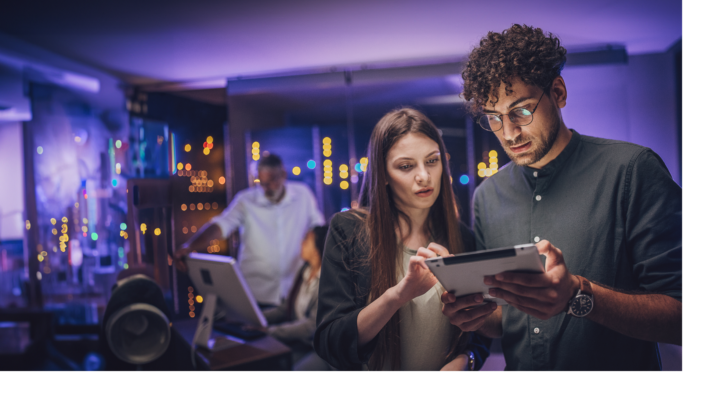 Male and female maintenance engineers examining data on digital tablet together in server room.