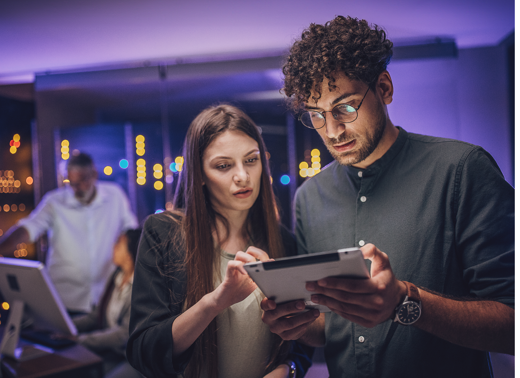 Male and female maintenance engineers examining data on digital tablet together in server room.