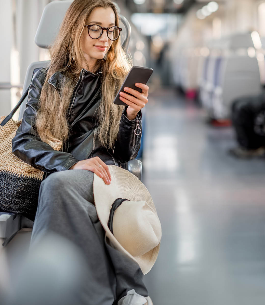Lifestyle portrait of a young businesswoman sitting with smart phone at the modern train