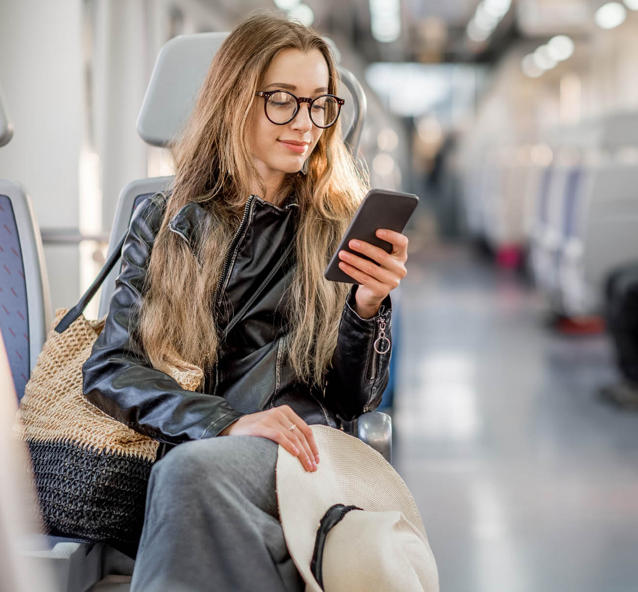 Lifestyle portrait of a young businesswoman sitting with smart phone at the modern train
