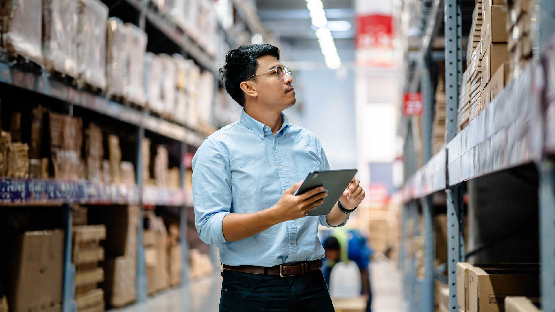 Businessmen or manager use a digital tablet to check the stock inventory on shelves in large warehouses, a Smart warehouse management system, supply chain and logistic network technology concept.