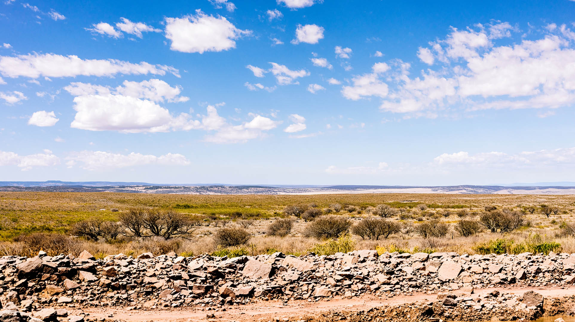 A horizon of rural land in Utah, USA, with the asphalt surface of the highway in the foreground.