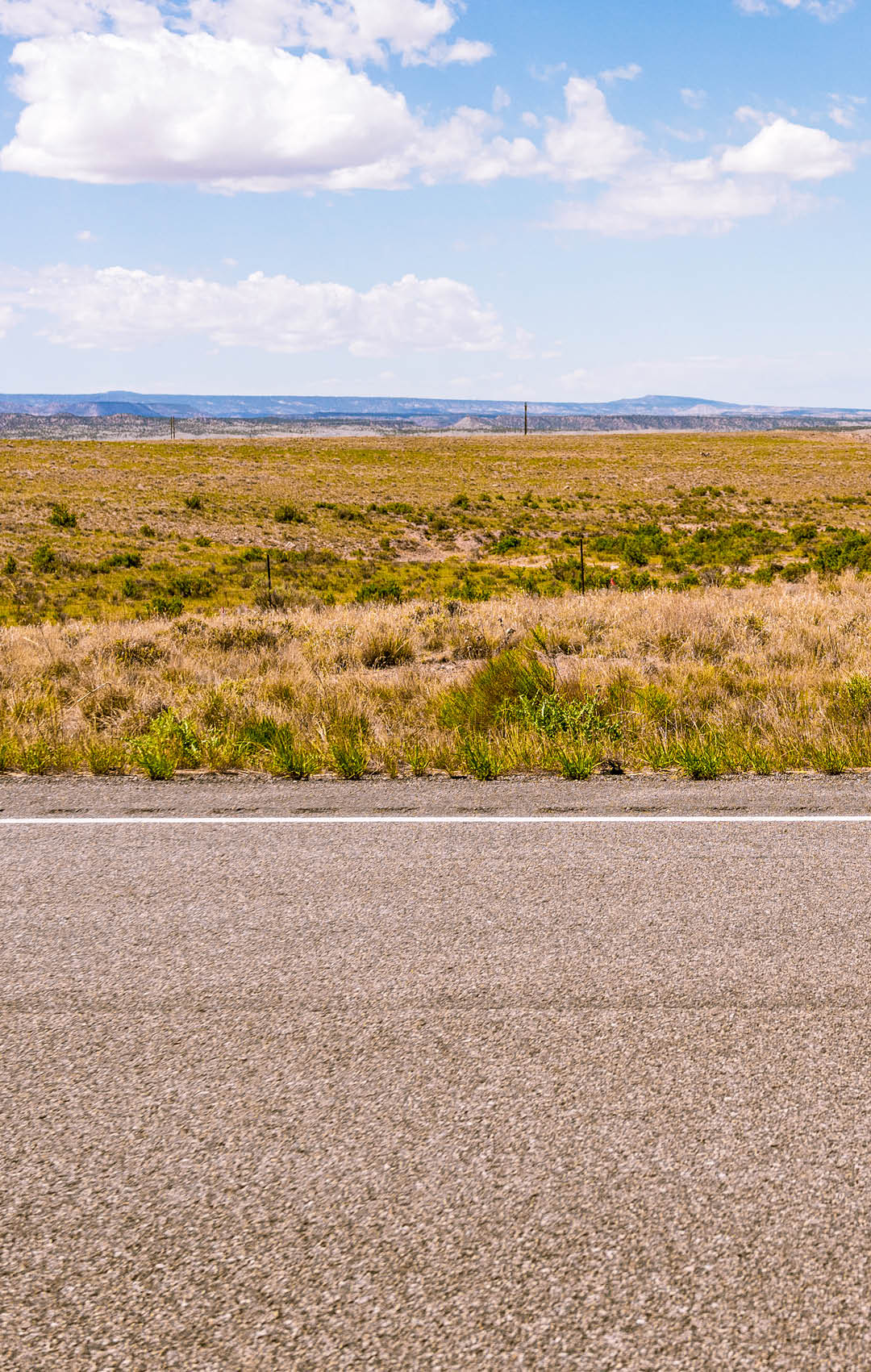A horizon of rural land in Utah, USA, with the asphalt surface of the highway in the foreground.