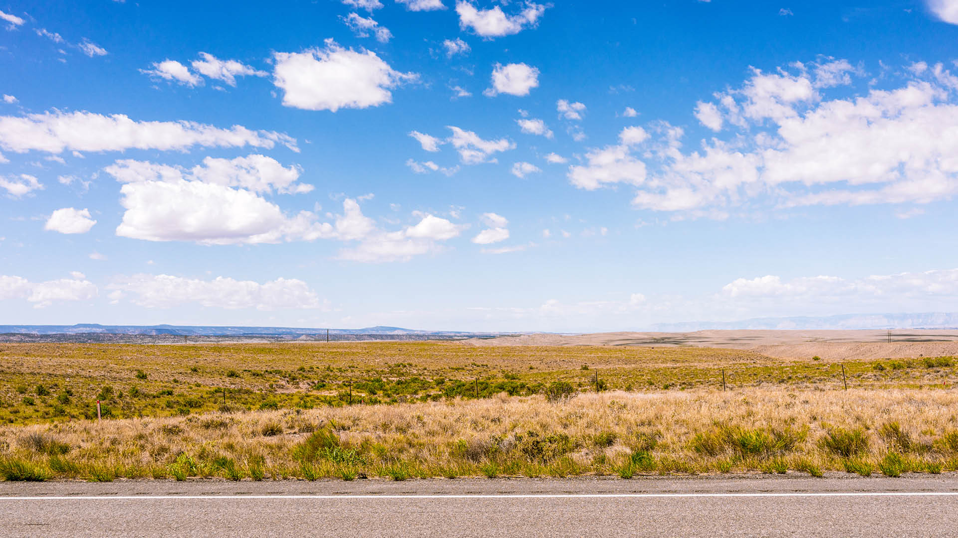 A horizon of rural land in Utah, USA, with the asphalt surface of the highway in the foreground.