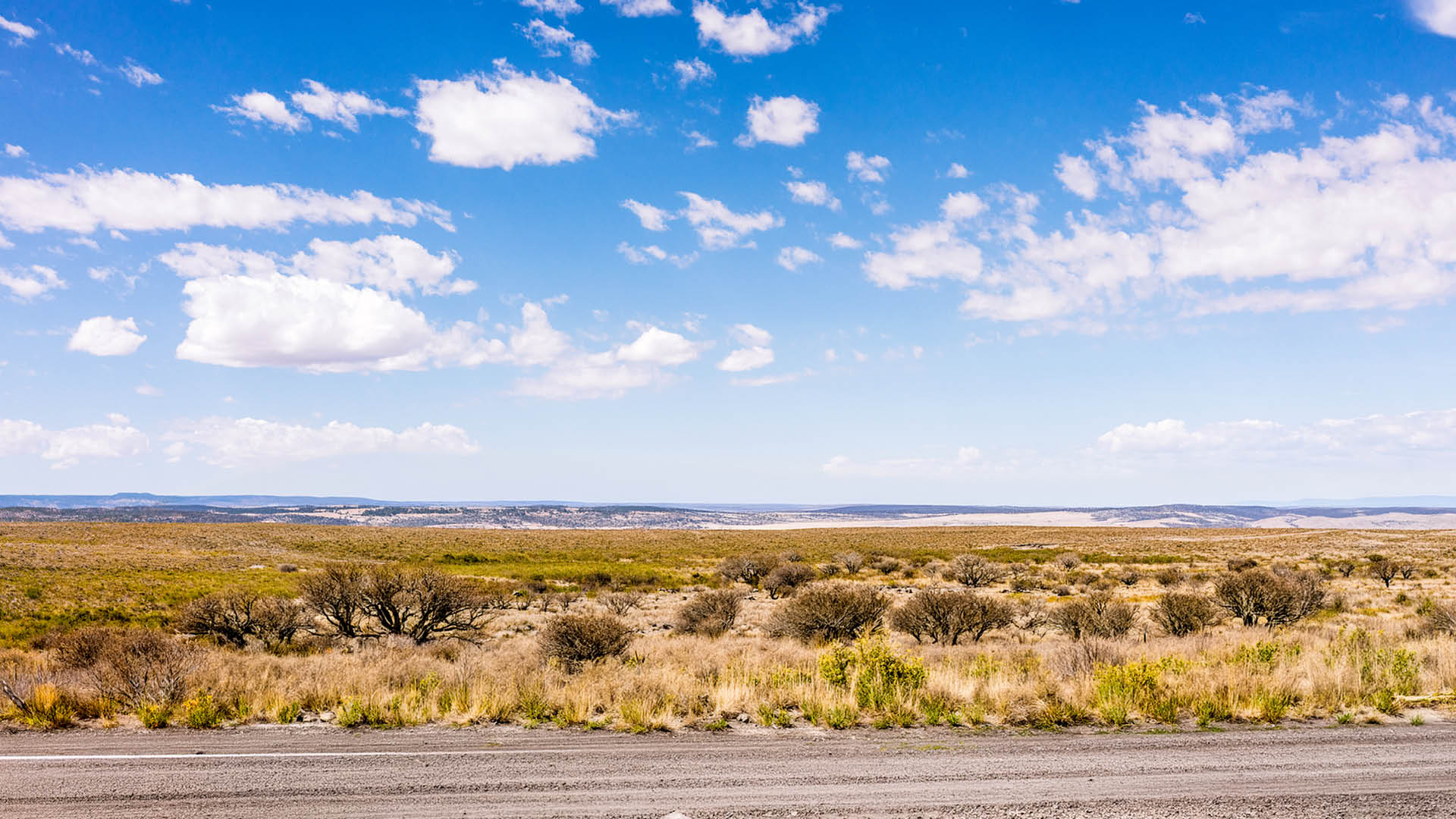 A horizon of rural land in Utah, USA, with the asphalt surface of the highway in the foreground.