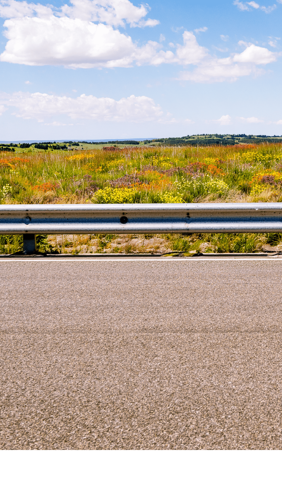 A horizon of rural land in Utah, USA, with the asphalt surface of the highway in the foreground.