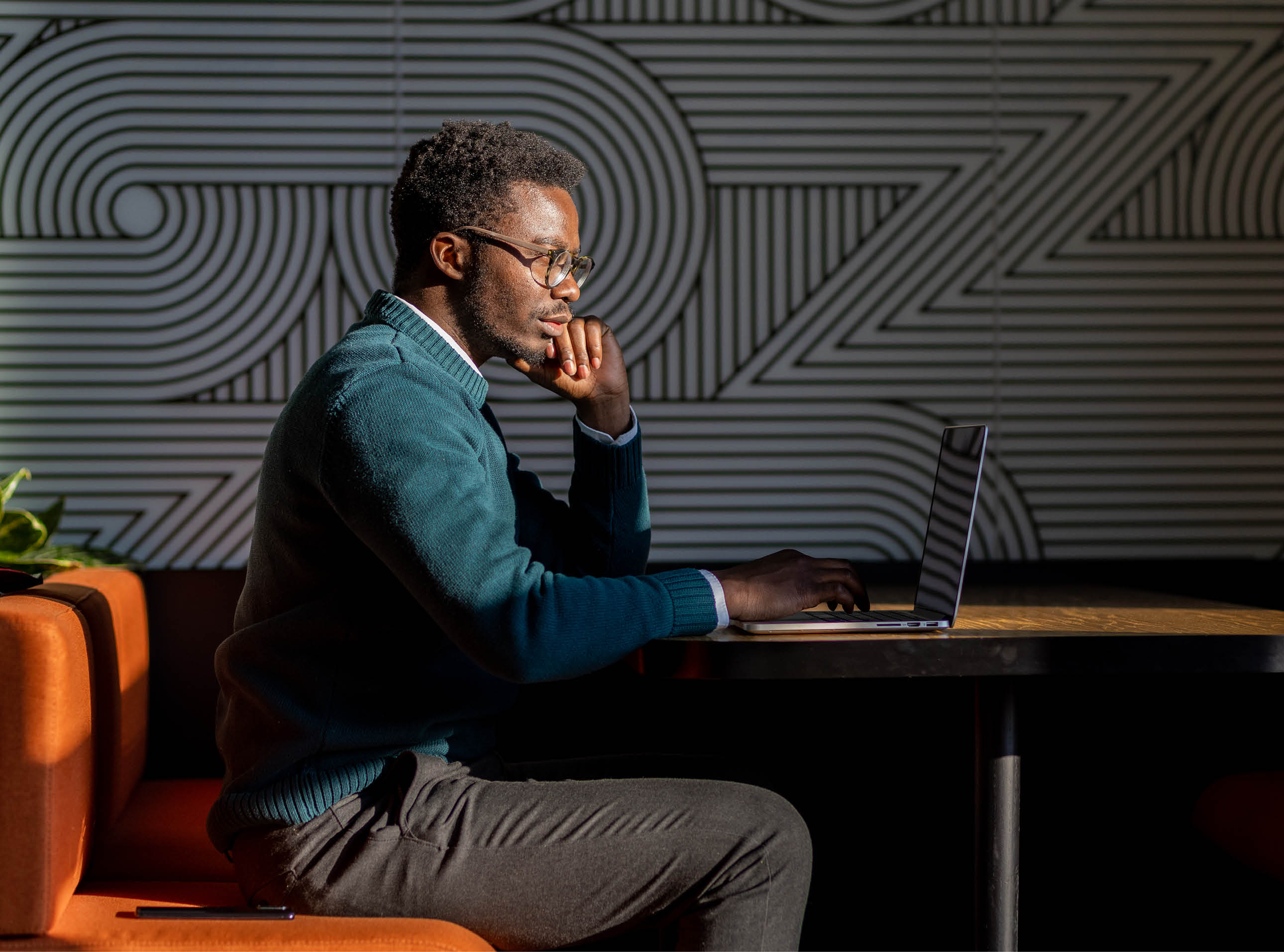 Young black businessman in a coworking space, new office, modern environment. Young African-American freelancer working on his laptop in a beautifully sunlit space.