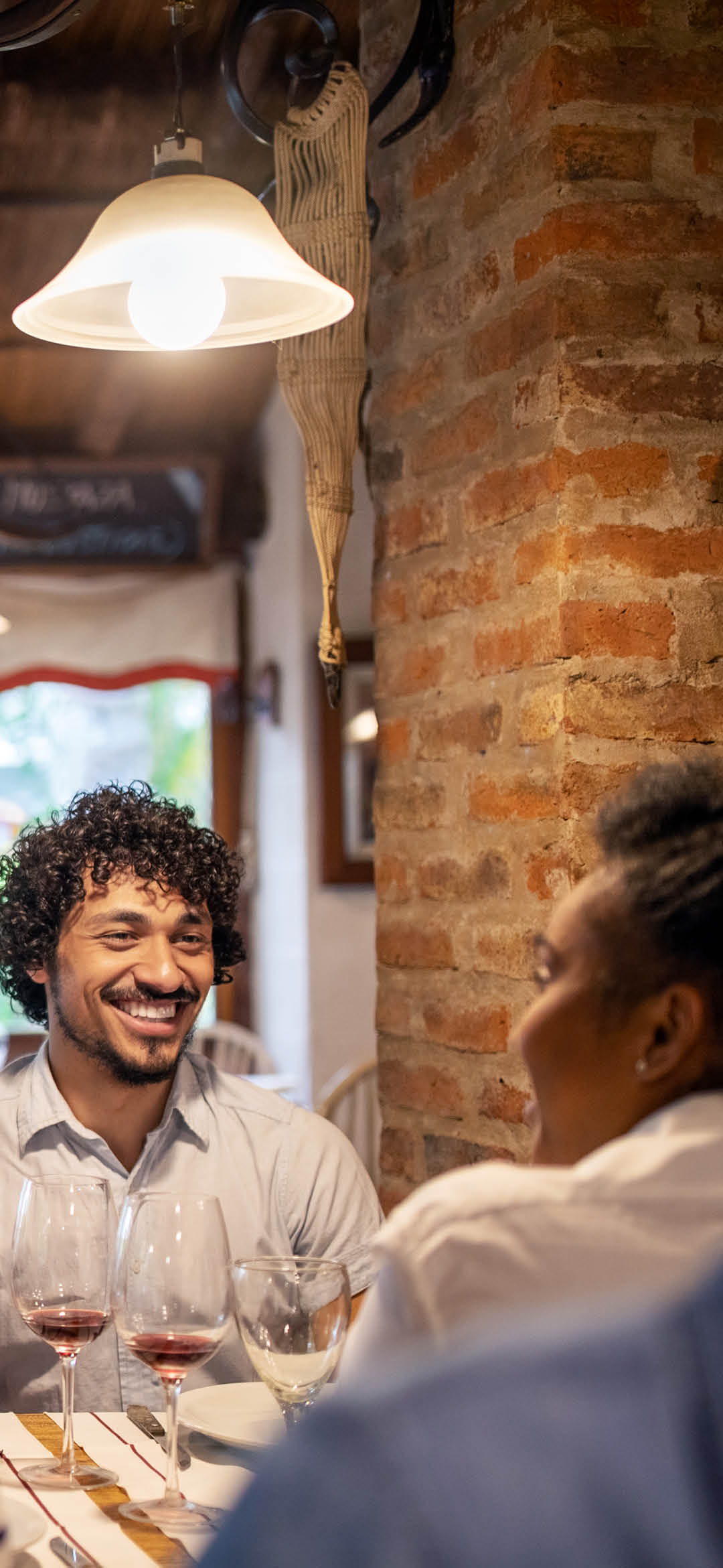 Smiling waitress using a digital tablet while taking lunch order from guests sitting at a restaurant table. Woman working at a restaurant taking order from a group of people.