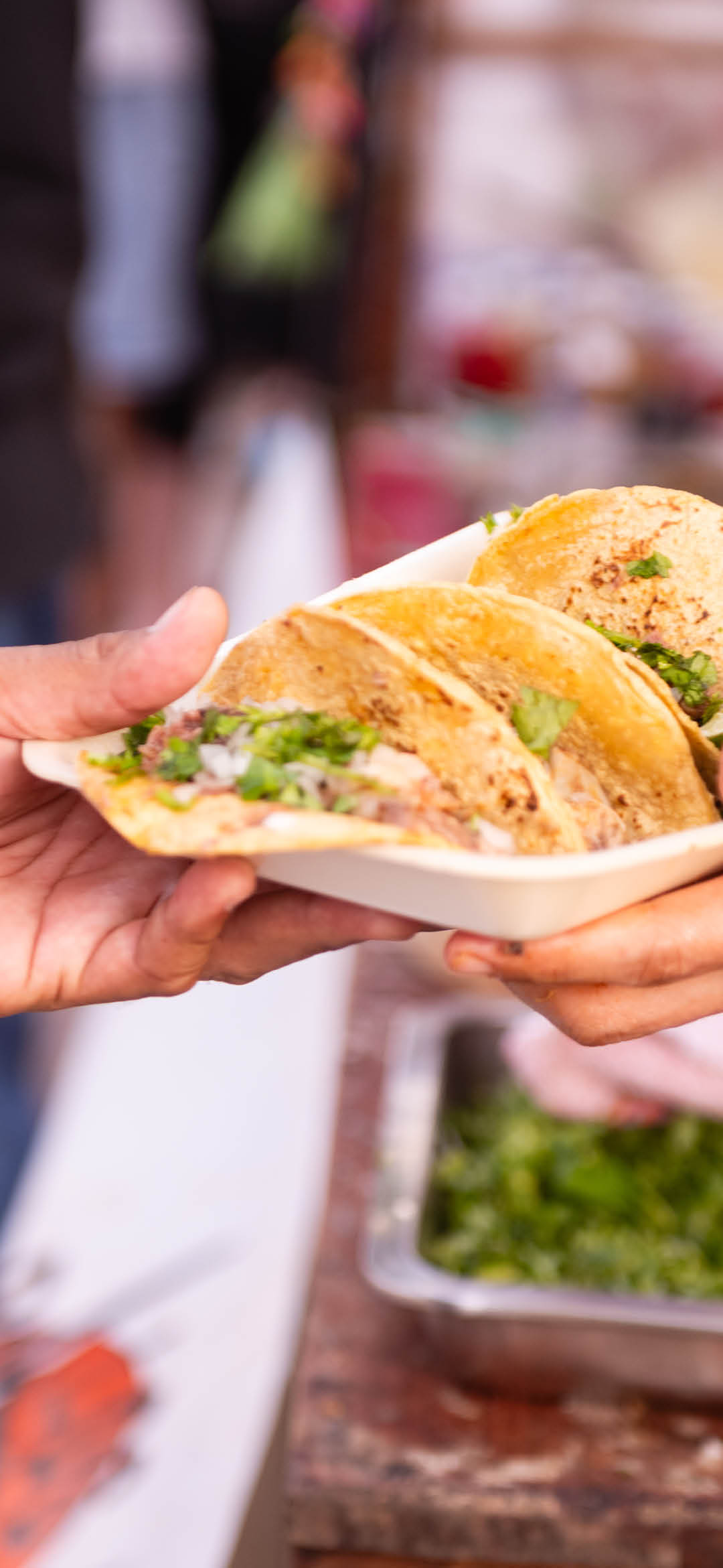 During the Dia de los Muertos holiday celebrations the hands of an unrecognizable person hands a plate of tacos to a customer outdoors in Playa del Carmen, Mexico.