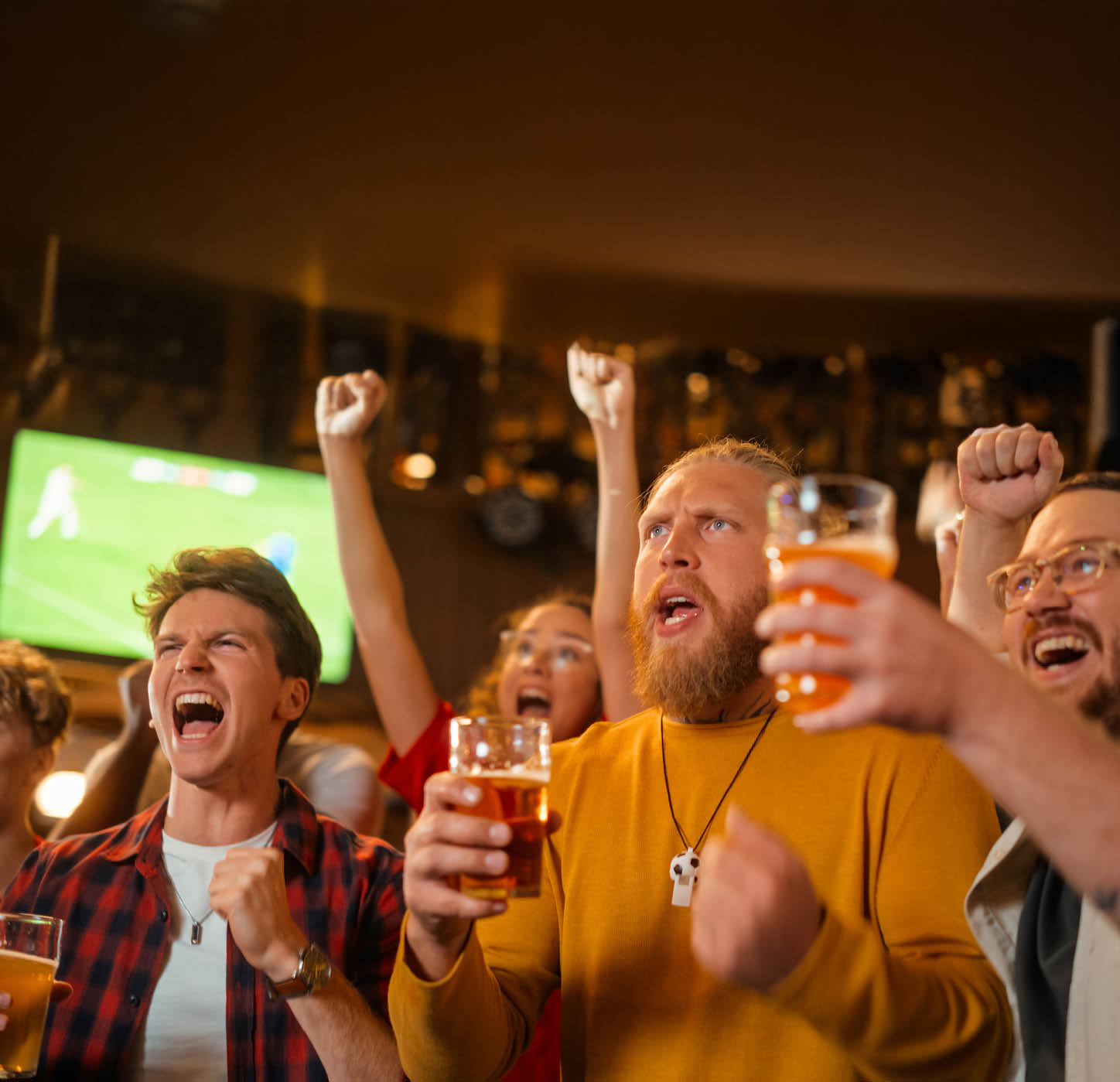Soccer Club Members Cheering for Their Team, Drinking Beer in a Pub. Supportive Fans Standing in a Bar, Cheering, Raising Glasses and Shouting. Friends Celebrate Victory After the Goal.