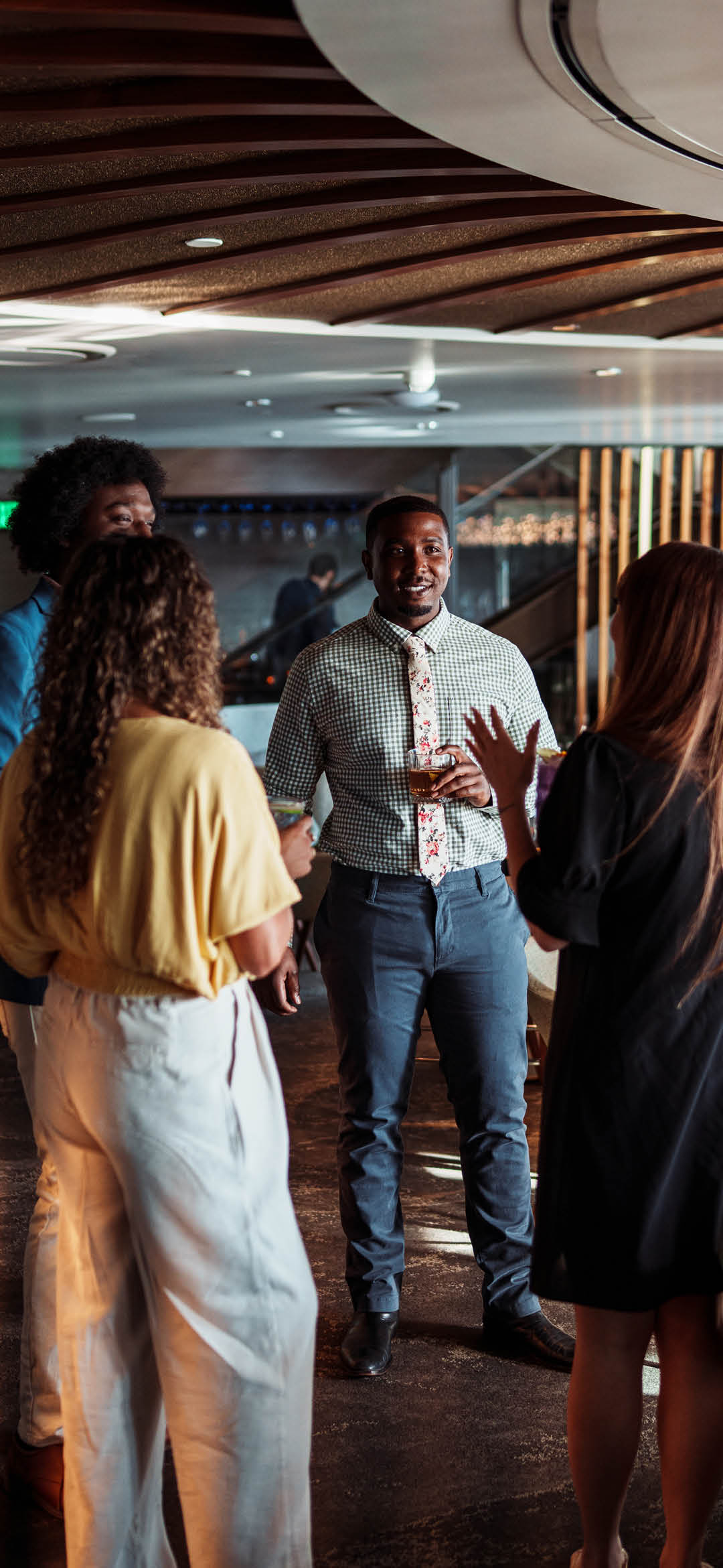 A multiracial group of male and female colleagues and friends having fun networking and socializing after work at the bar of an upscale restaurant during happy hour.
