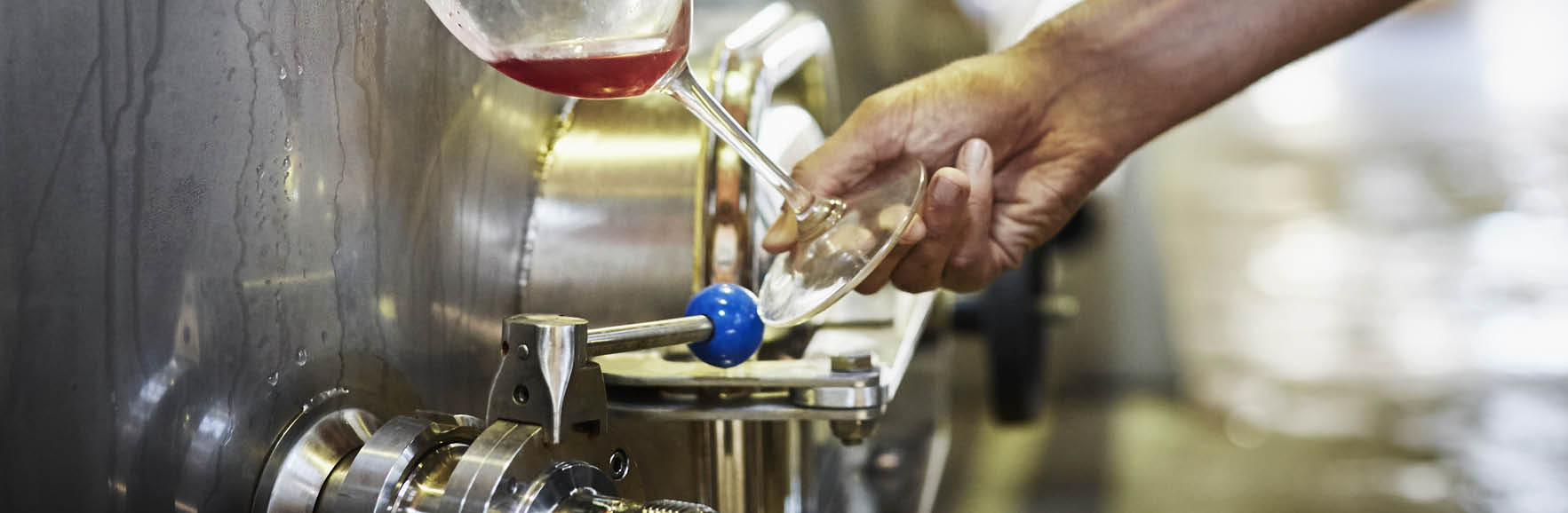 Cropped image of man filling wine from storage tank in winery