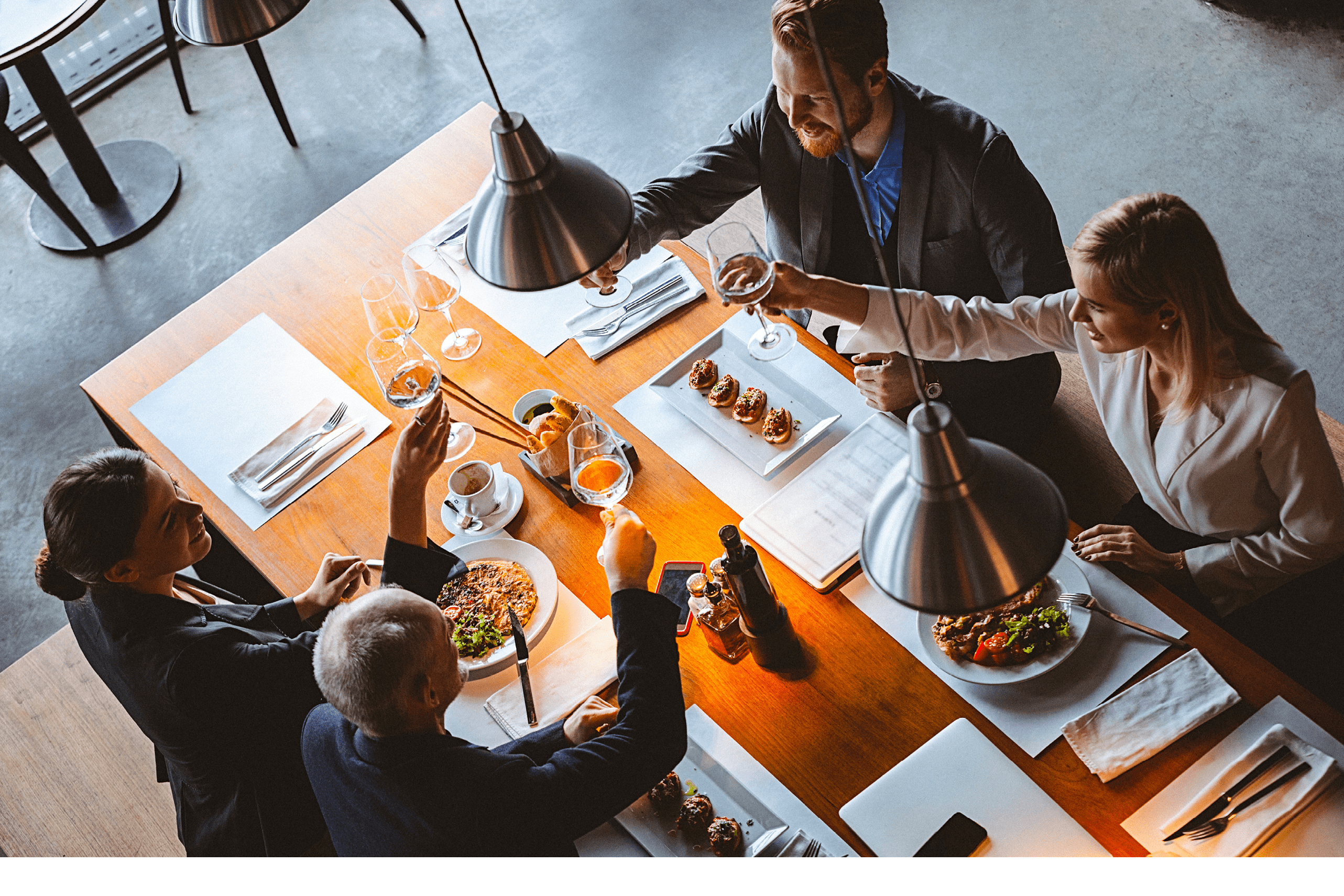 High angle view photo of a group of friends toasting during lunch time in a high-end reastaurant  It could be that they are business people having a business lunch  All are well dressed  The shot is executed with available natural light and the copy space has been left 